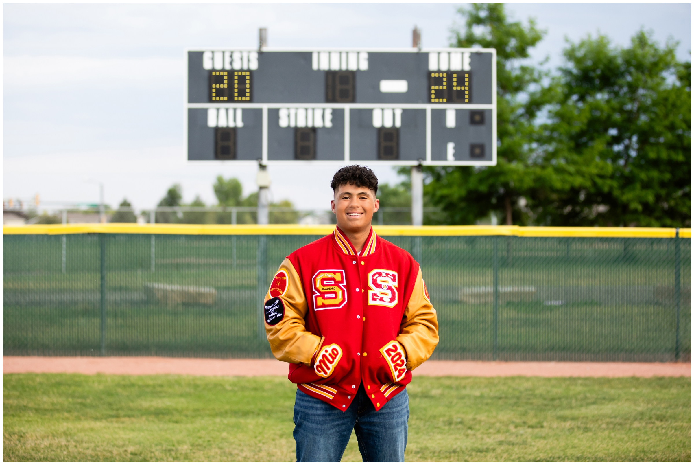 teen baseball player posing in front of scoreboard during Longmont senior pictures at Skyline High School 