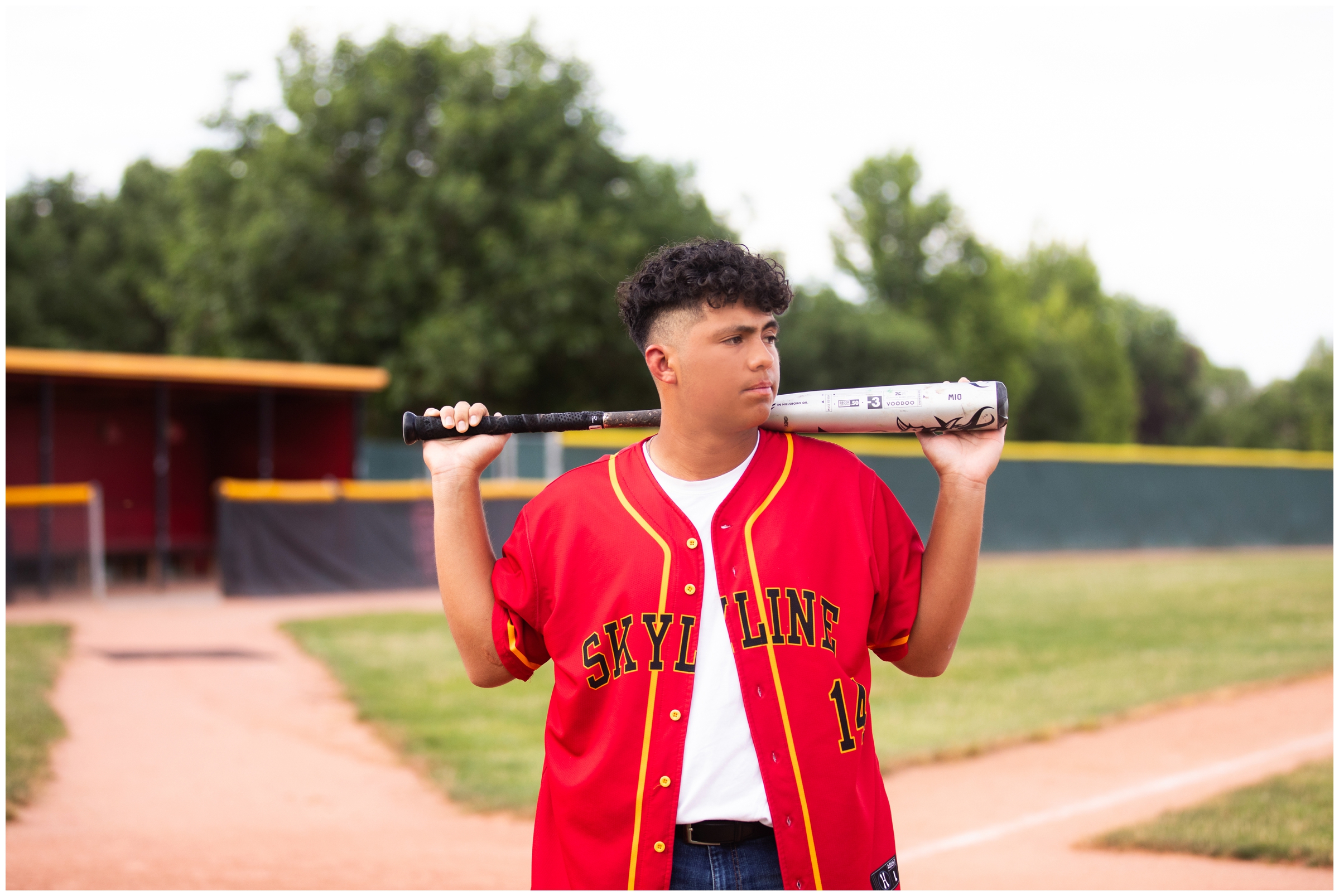 teen guy posing with baseball bat during Longmont Colorado senior pictures