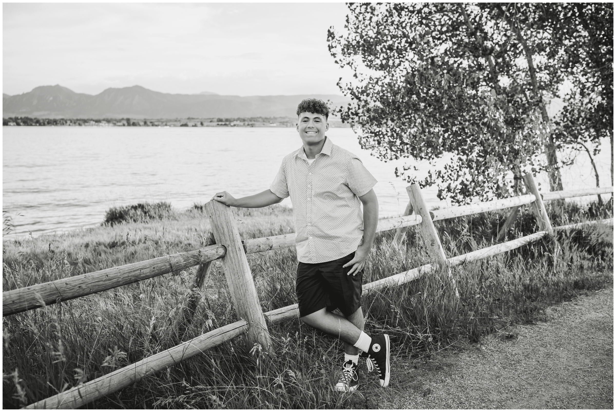 teen boy leaning against wooden fence during Boulder Colorado senior portraits at Coot Lake 