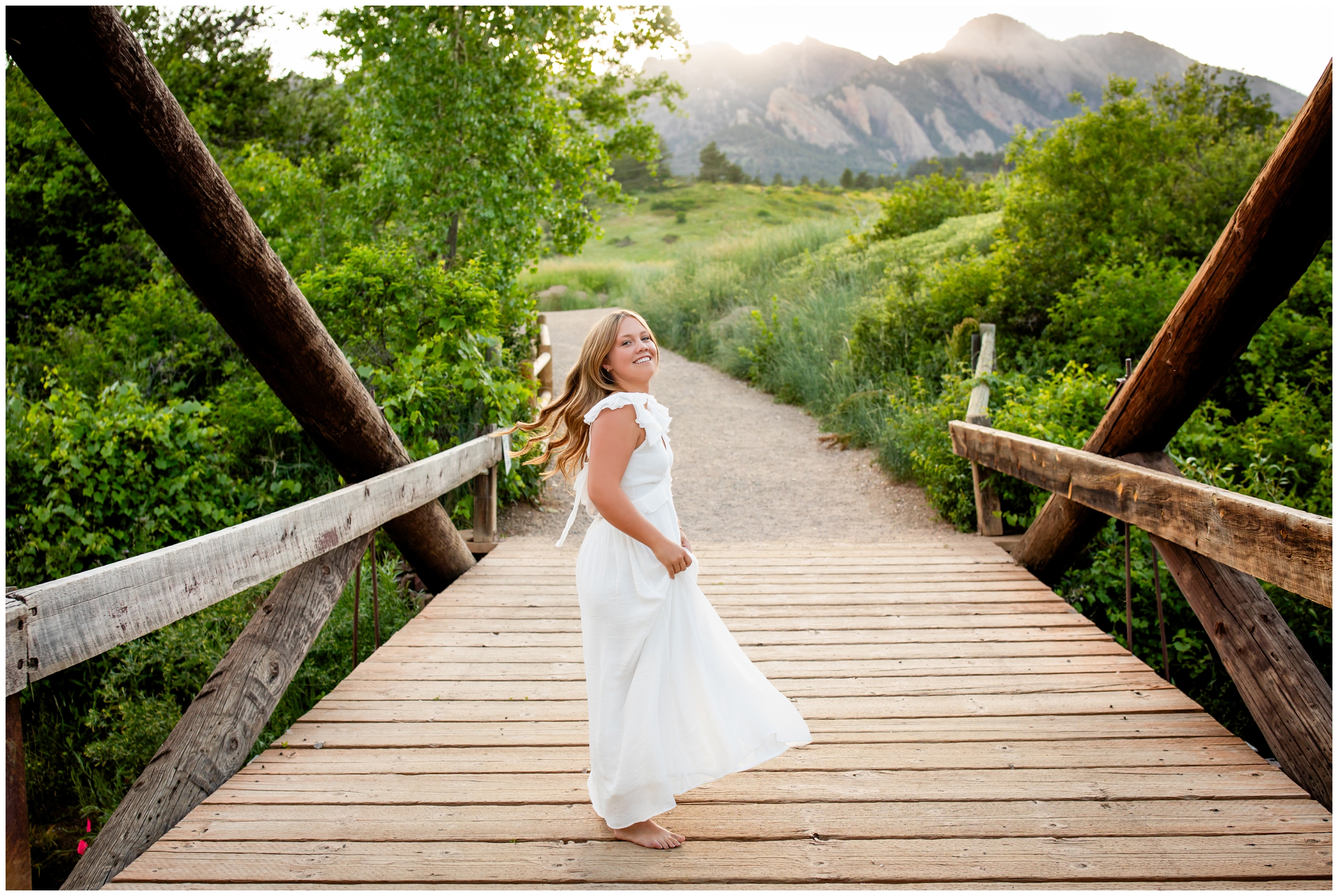 high school senior twirling on wooden bridge during Colorado summer senior pictures at South mesa trail 