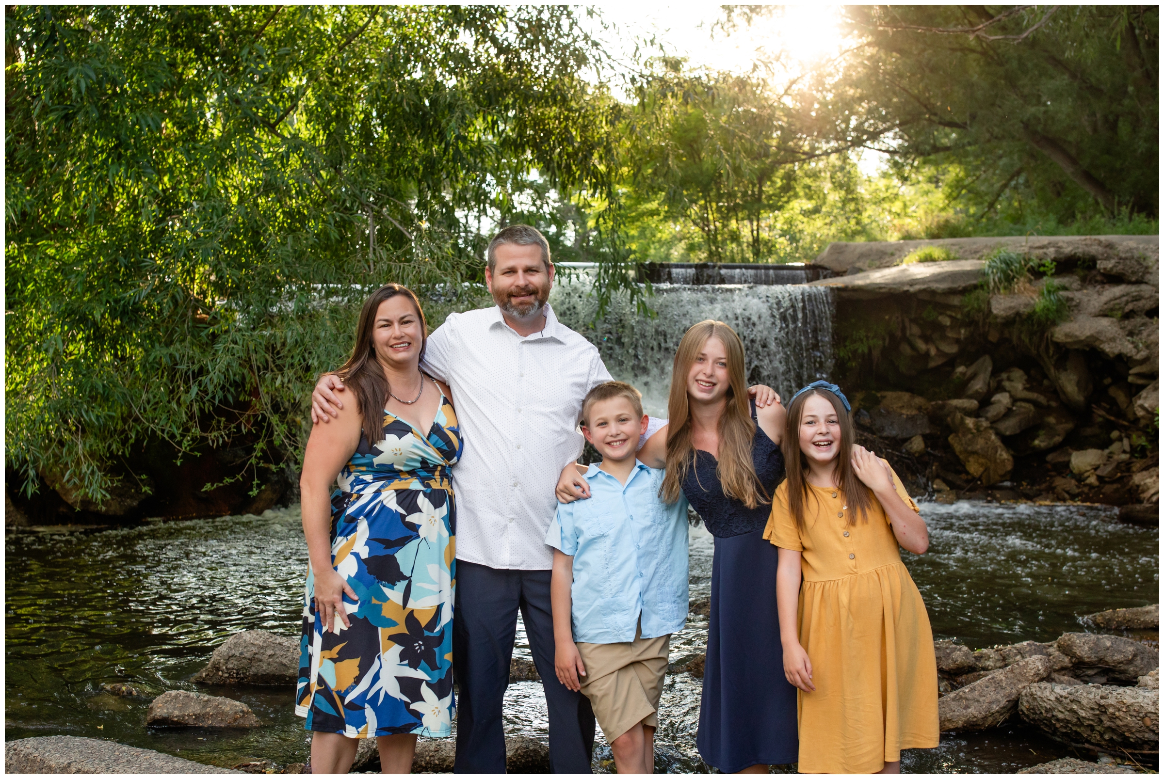 family posing in front of waterfall during Longmont portrait photography session at Golden Ponds 