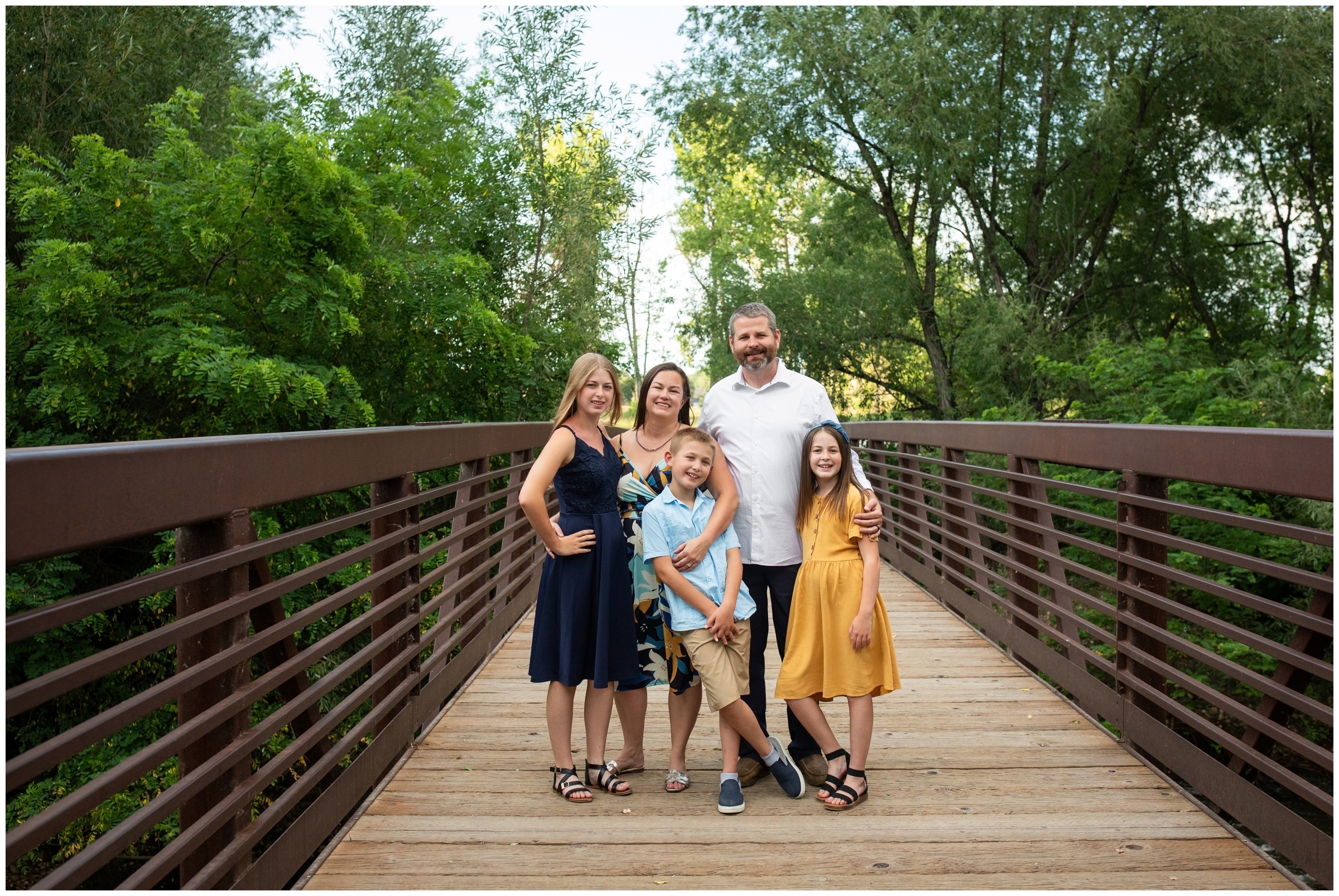 family posing on bridge during Longmont Colorado family portraits at Golden Ponds 