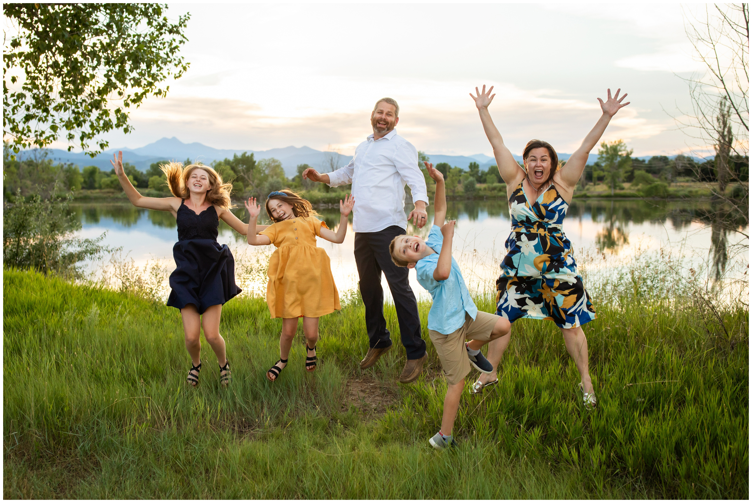 family jumping with mountains in background during candid family photos in Longmont Colorado 