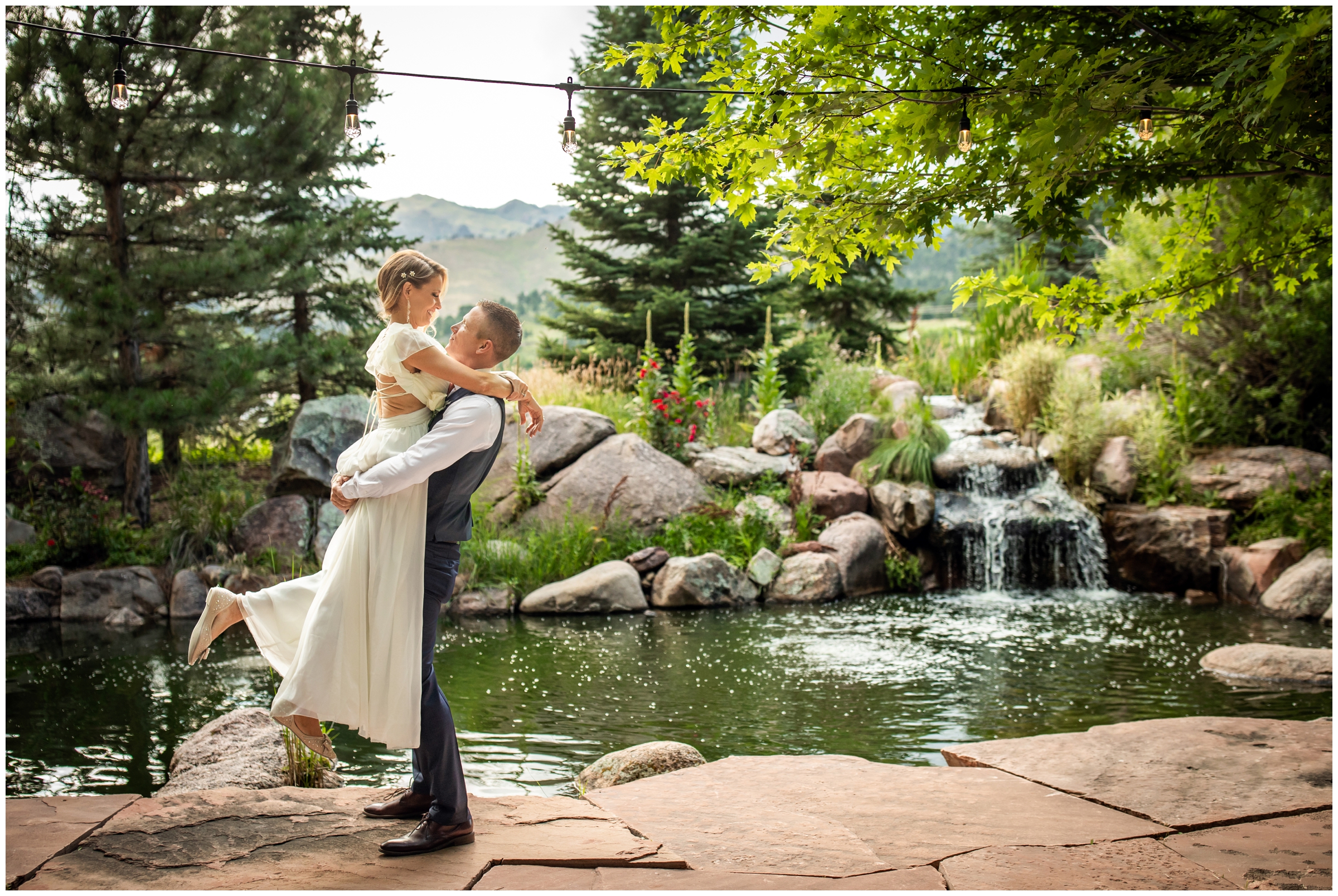 groom lifting bride in front of small waterfall and ponds at the Greenbriar Inn during Boulder wedding portraits by Plum pretty photography 