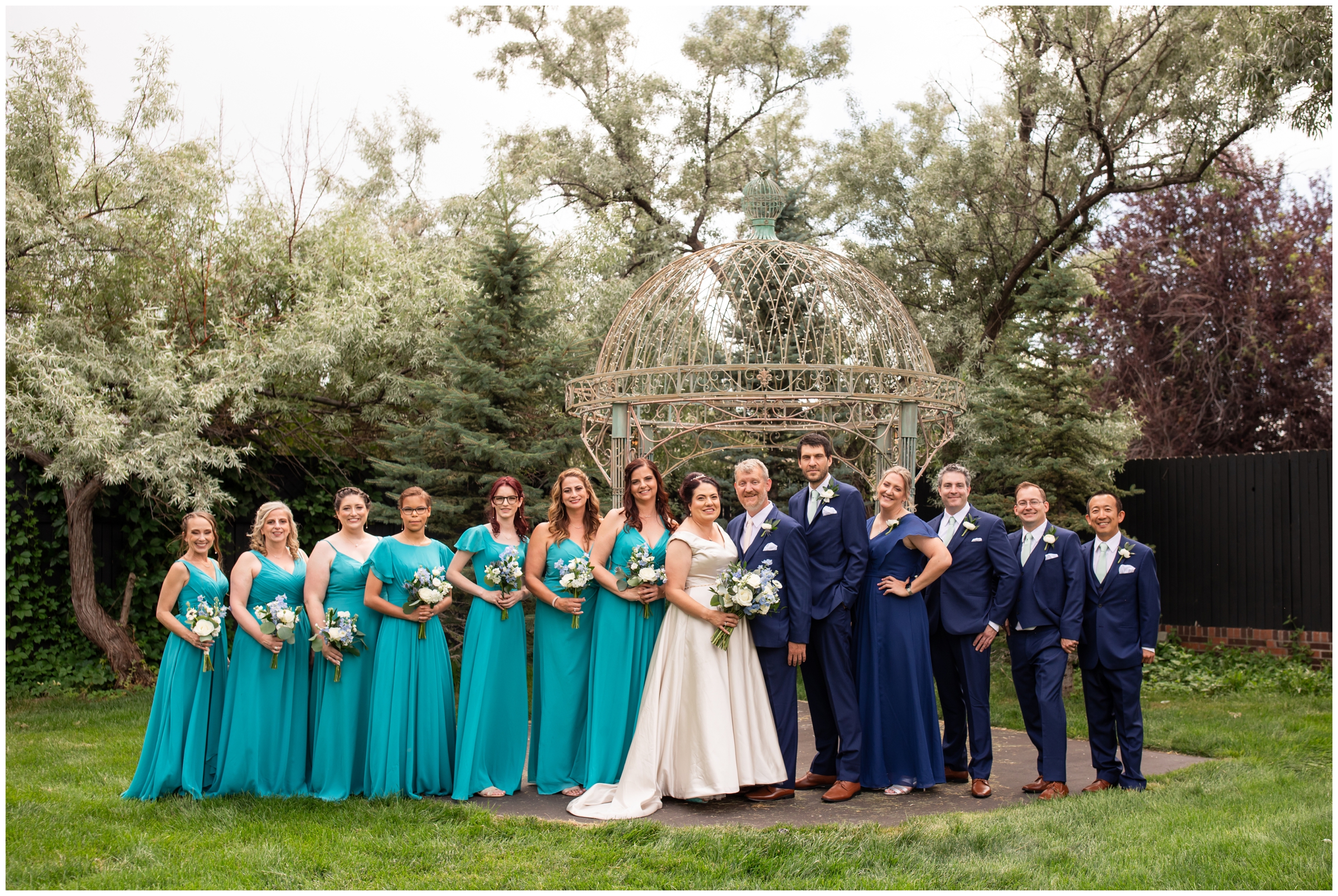 wedding party in aqua and navy blue posing in front of gazebo at Lionsgate Event Center wedding in Colorado 