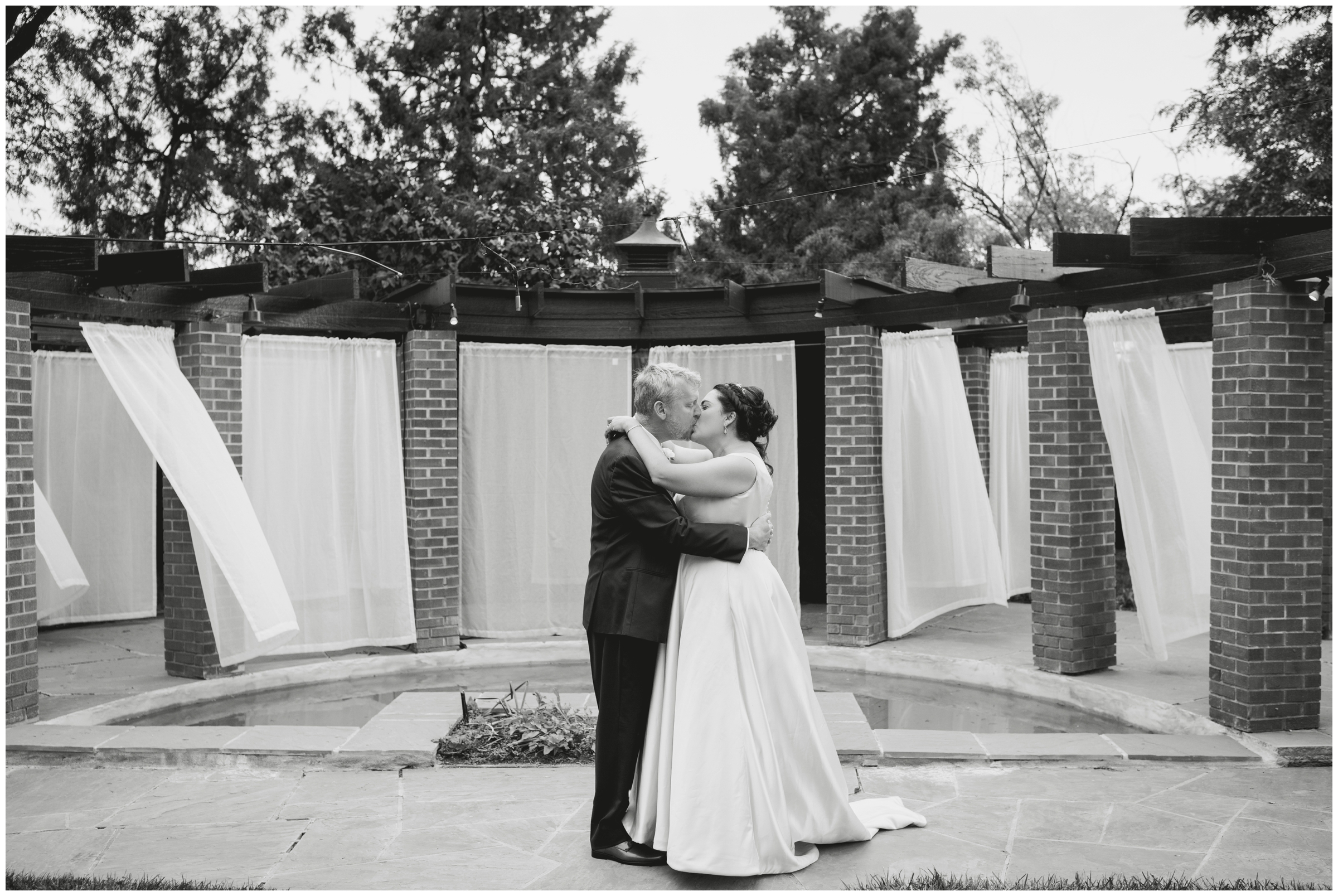 couple kissing in front of water fountain during Dove House wedding pictures at Lionsgate event Center 