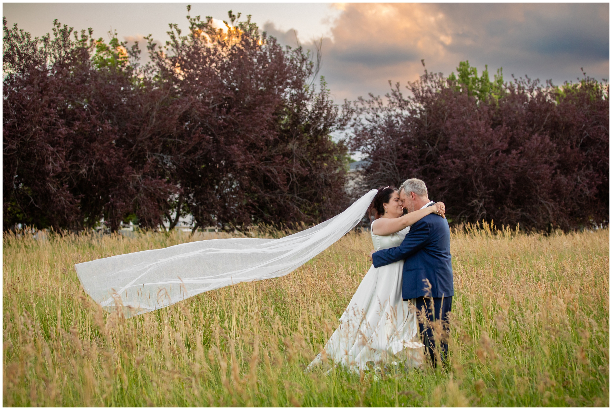 couple embracing in a field at sunset after their Chandelier Barn Colorado wedding