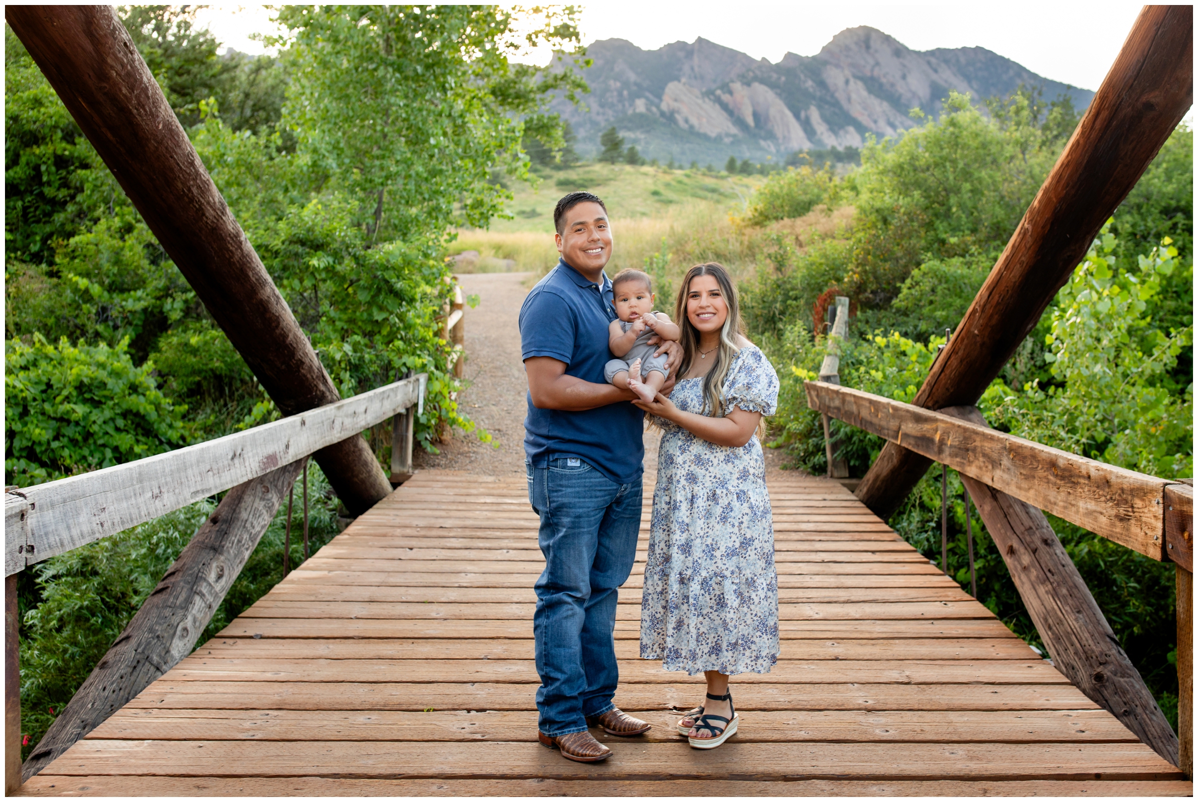 family of three posing on wooden bridge during Boulder family pictures at South Mesa