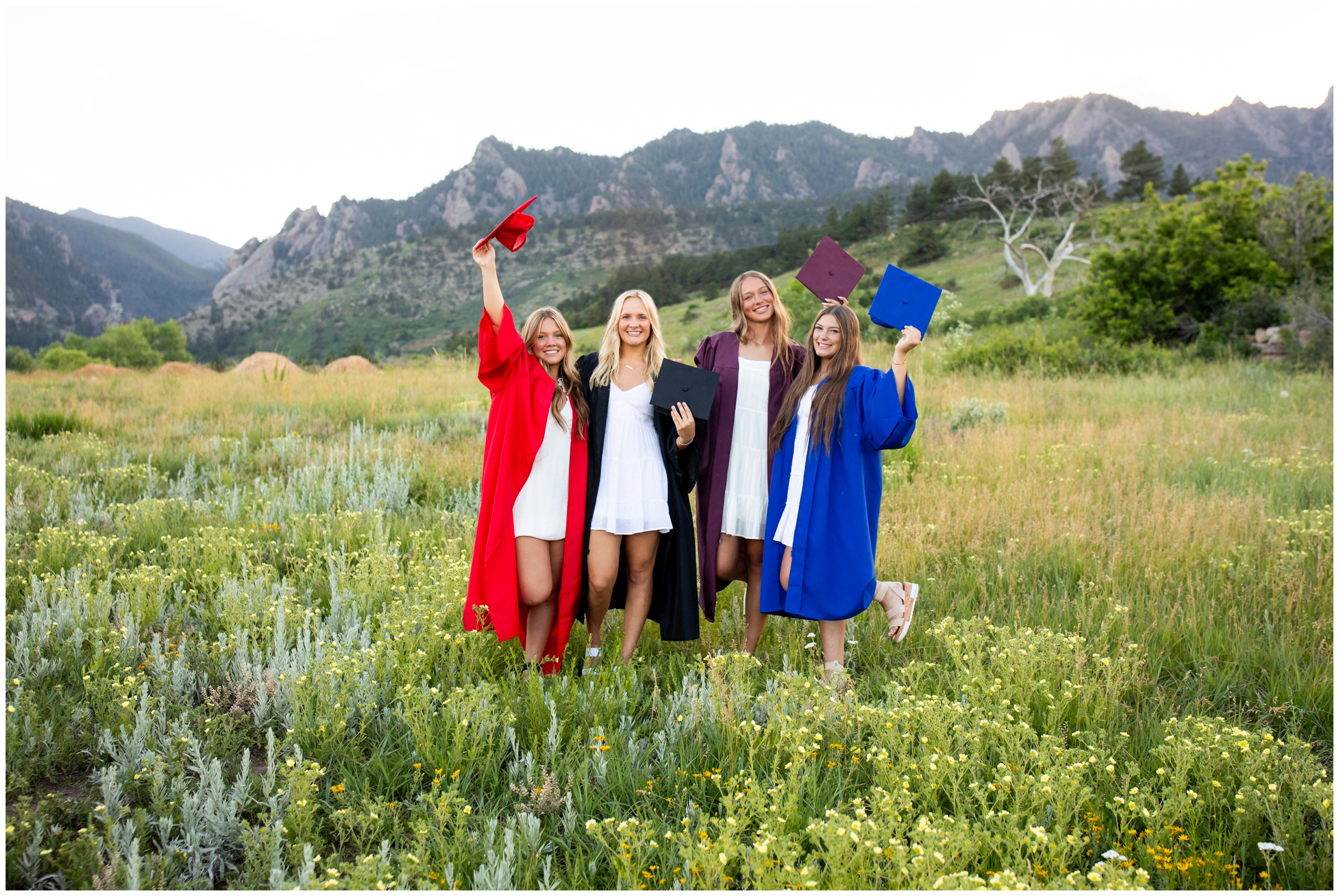 four teens in a mountain field with caps and gowns during Boulder Colorado graduation photography session  
