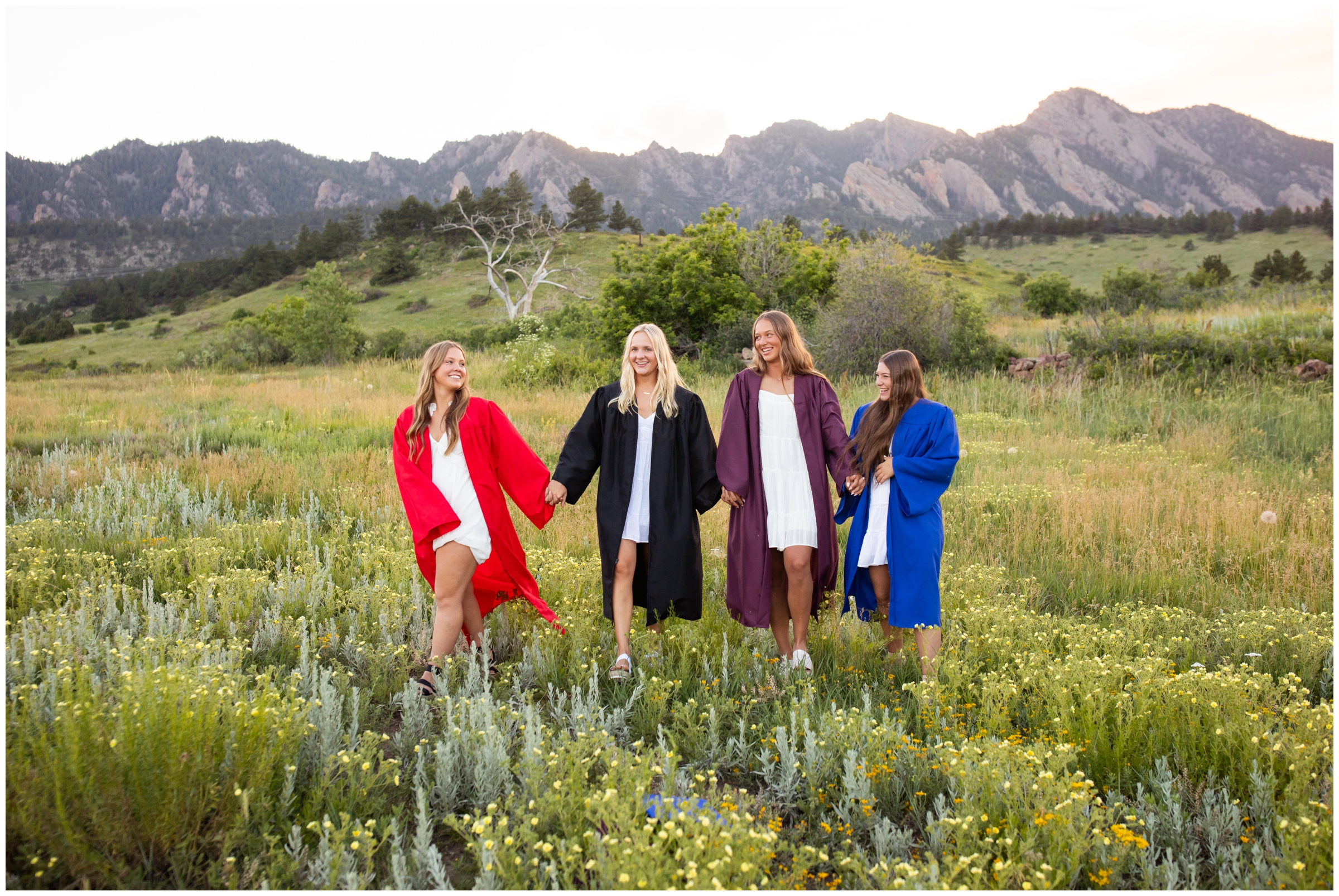 teens walking through a field during Boulder Colorado cap and gown photography session at South mesa trail