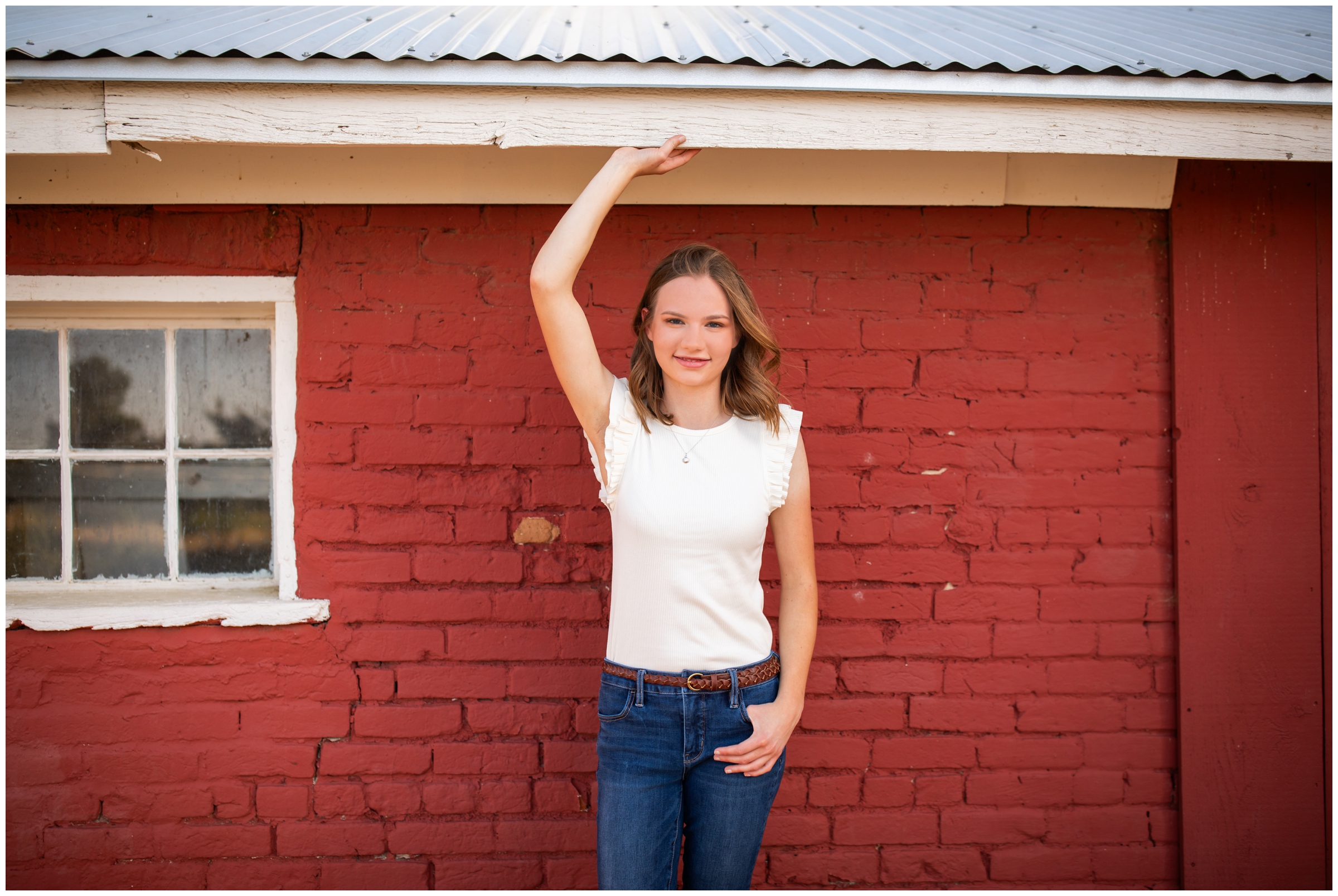 teen posing against red brick wall during Centennial Colorado senior pictures at 17 mile house