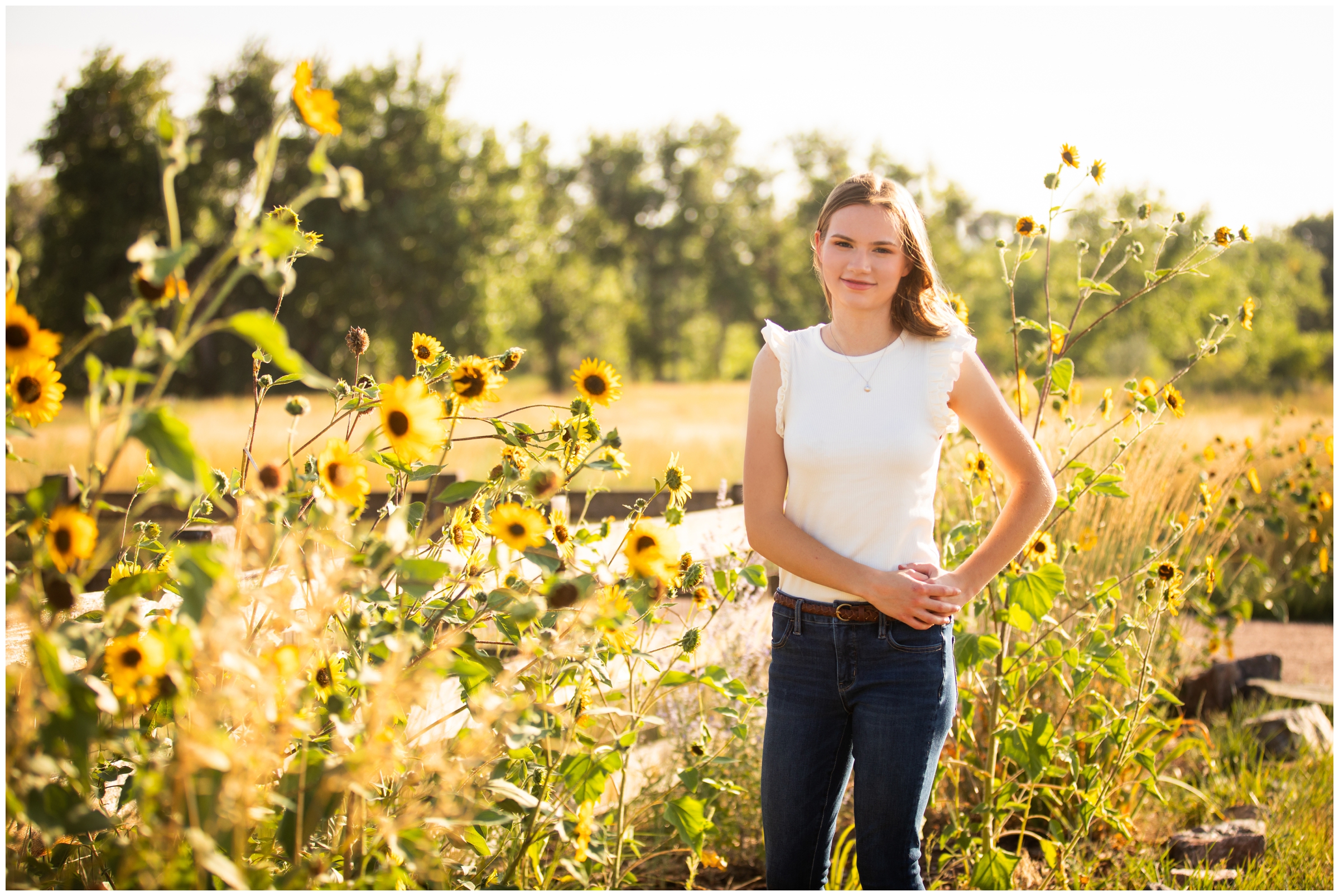 teen posing with sunflowers during Colorado high school graduation photography session 