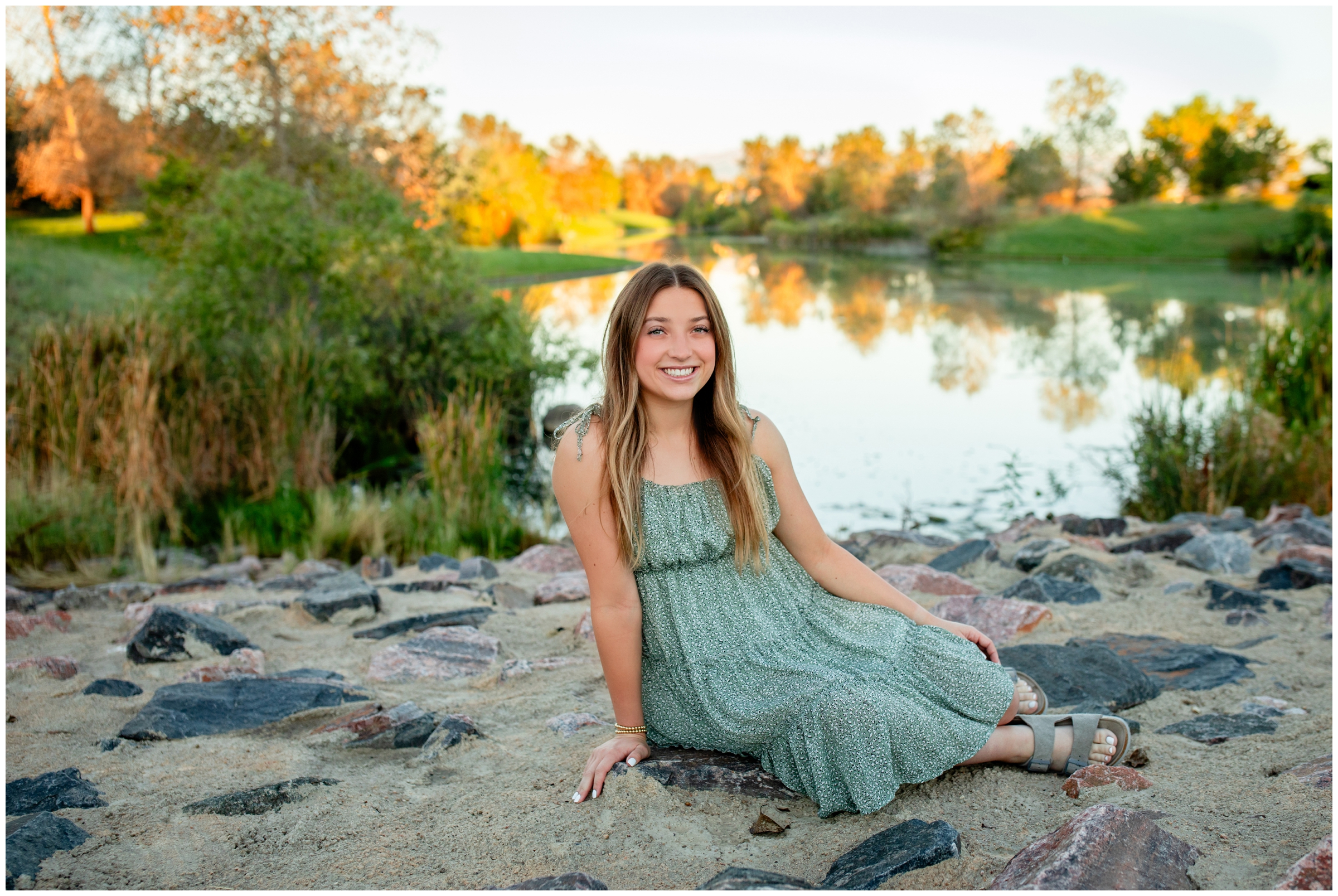 teen sitting in front of Buffalo Lake at sunrise during Broomfield Colorado senior pictures 