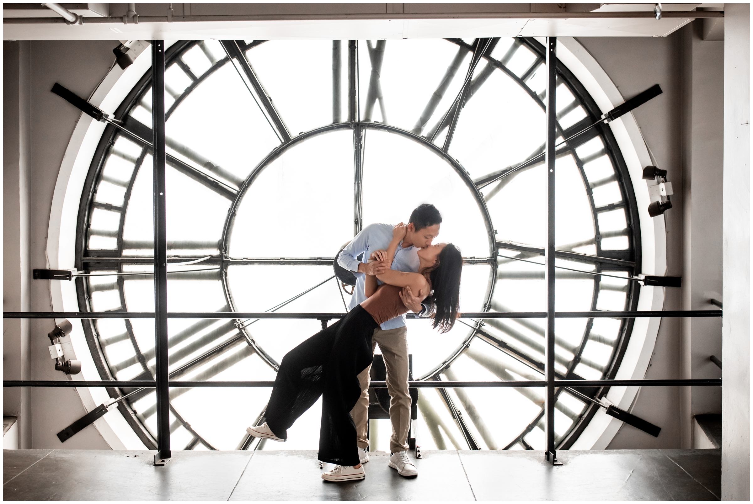 man dipping fiance in front of clock tower during denver engagement proposal photography session 