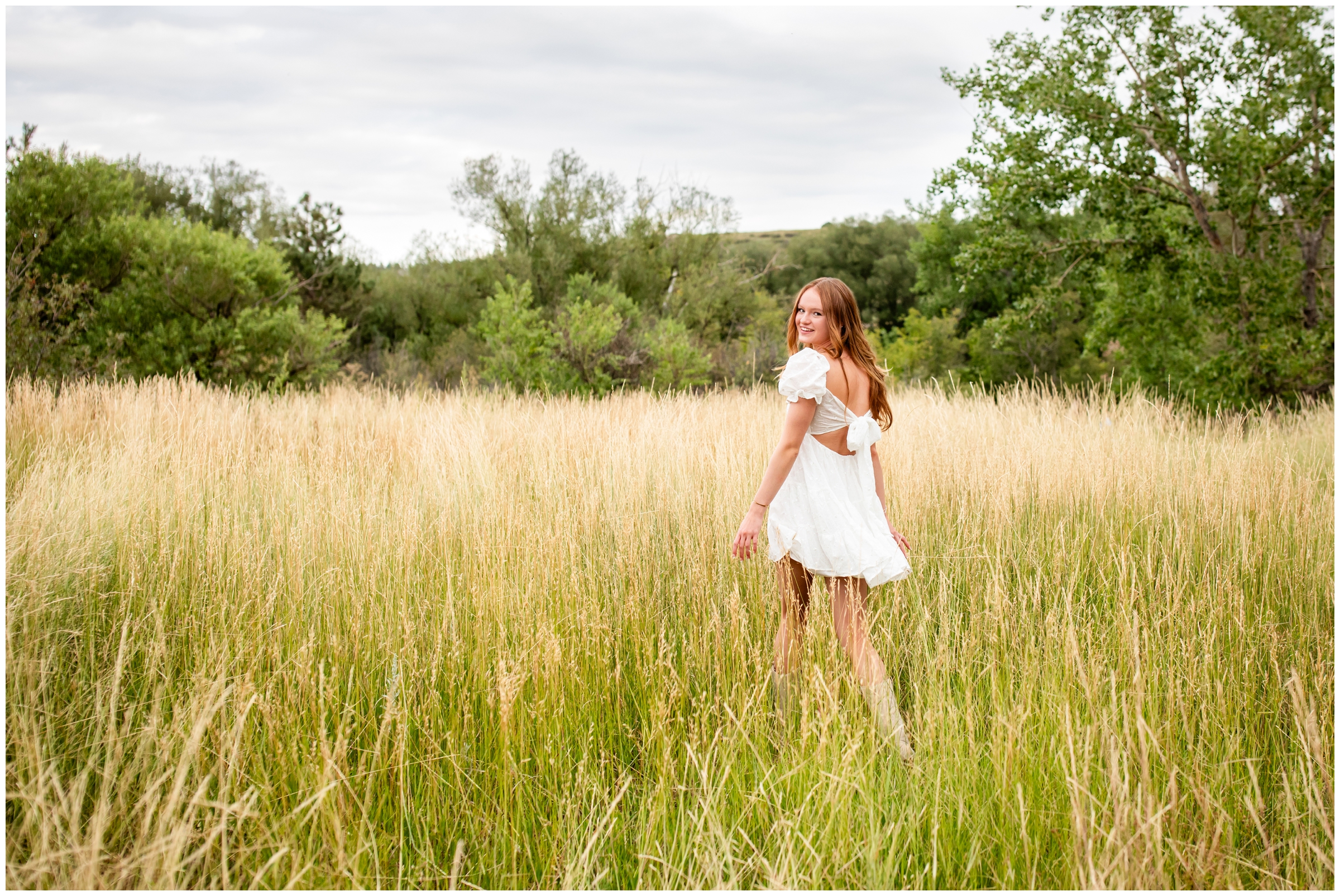 teen walking through field of long grasses during Prospect Ridge Academy senior photos in Boulder Colorado 