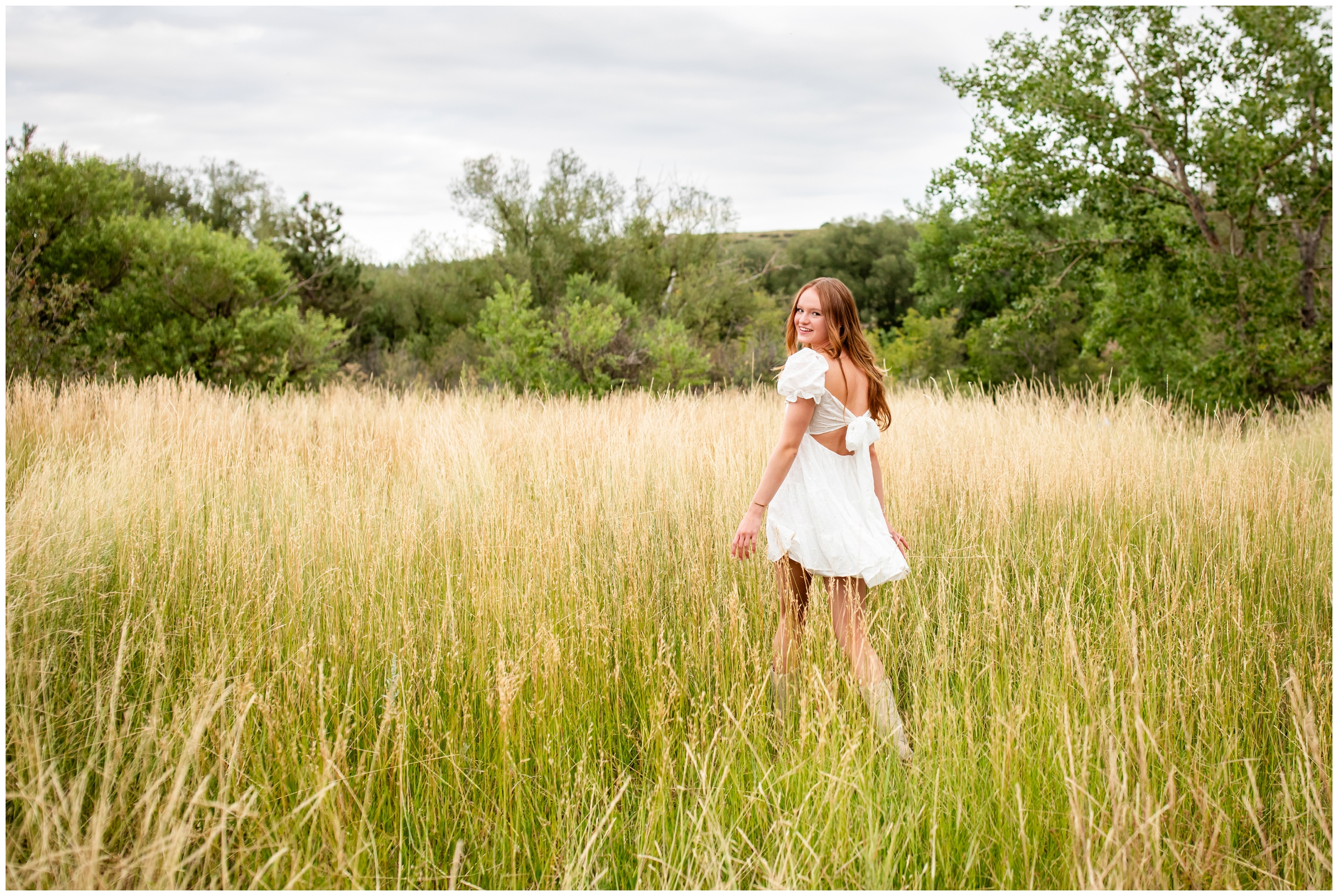 teen walking through field of long grasses during Prospect Ridge Academy senior photos in Boulder Colorado