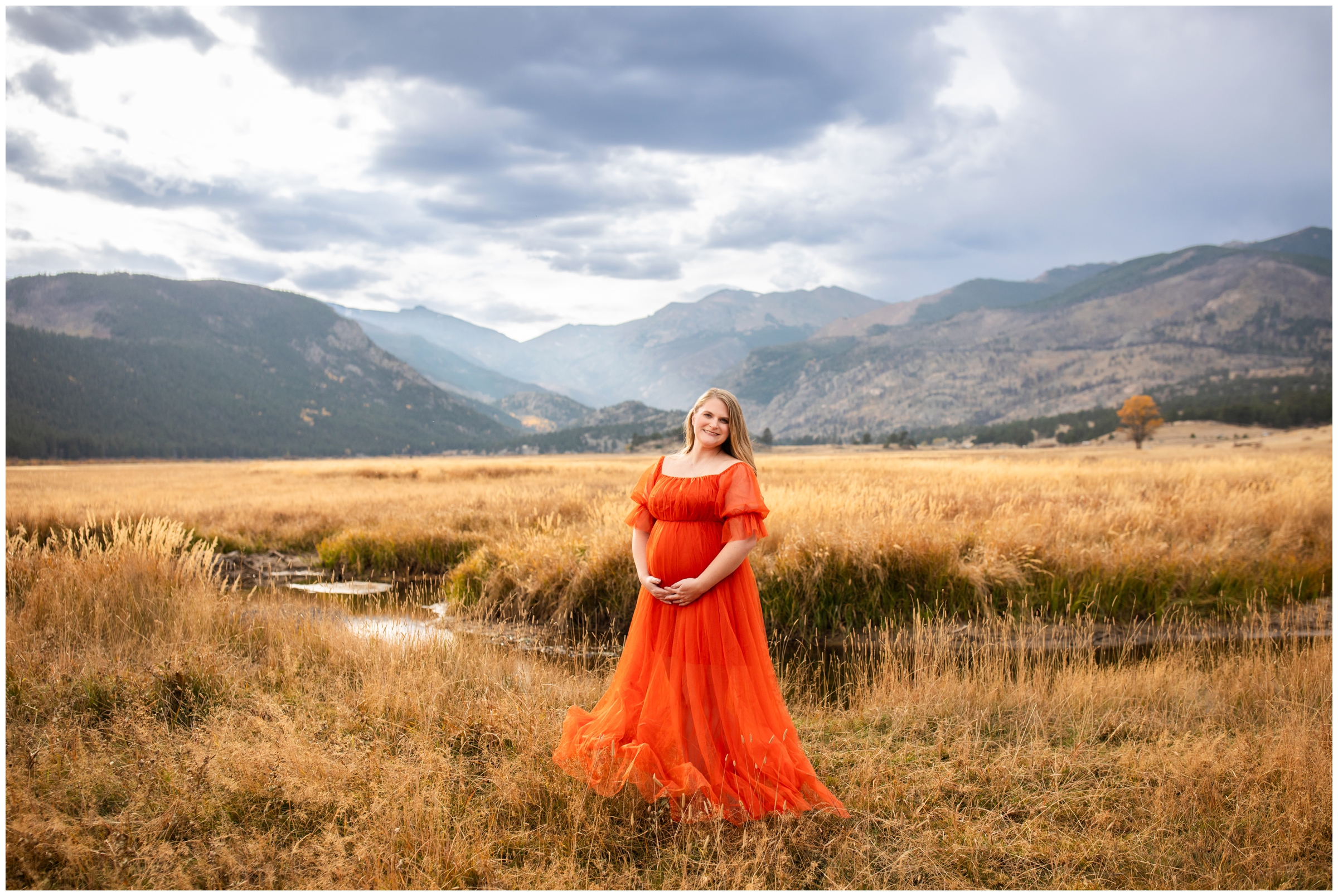 pregnant in orange dress posing in mountain field at Moraine Park during RMNP maternity photography session in Colorado 