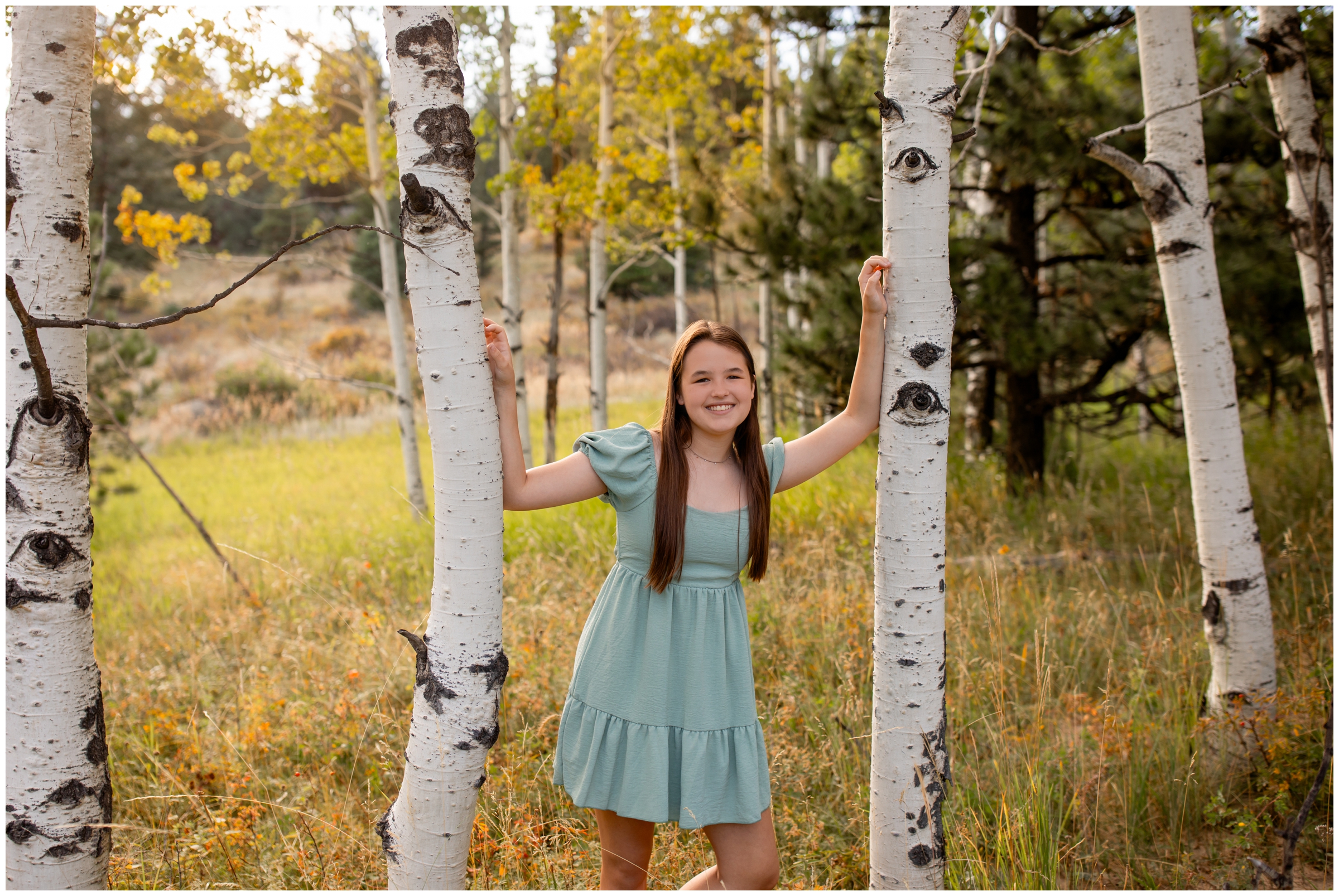teen leaning against aspen tree during fall senior pictures in the Colorado mountains 