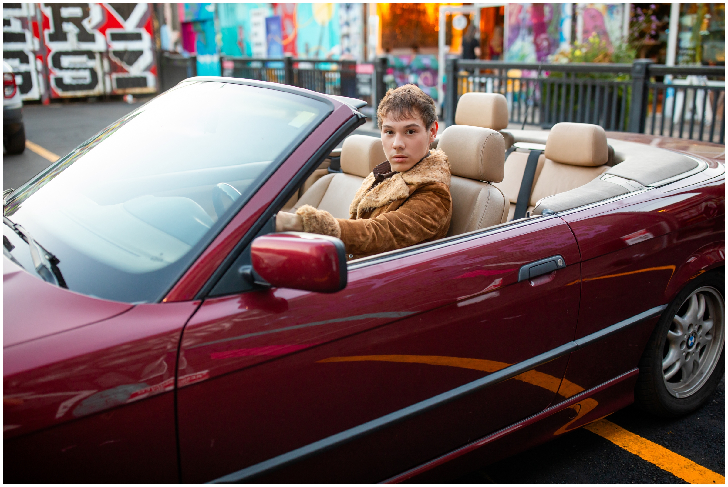teen guy posing in maroon BMW during Denver Colorado senior portraits in the RINO art district 