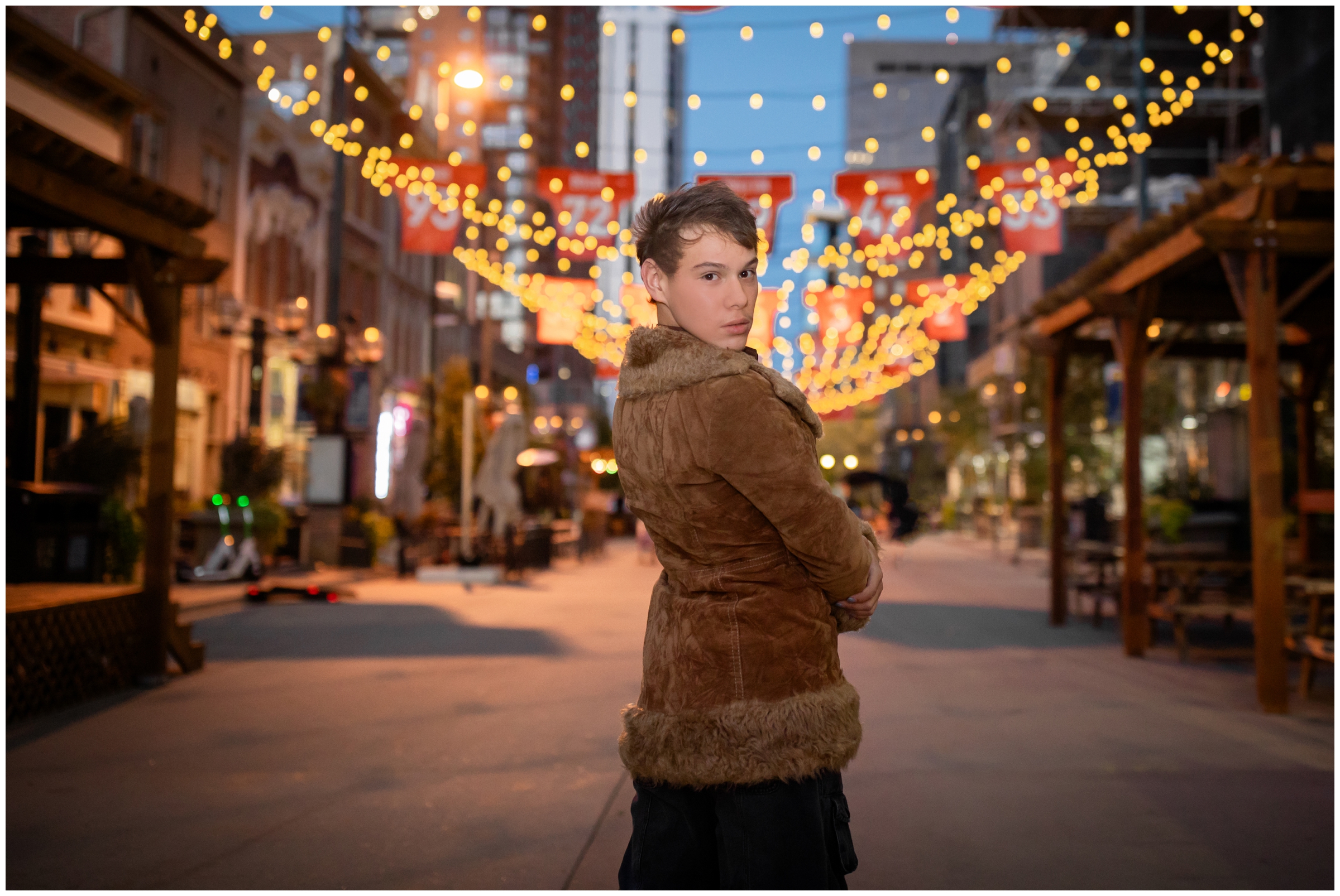 teen guy posing under the lights of Larimer Square during nighttime senior pictures in Denver Colorado