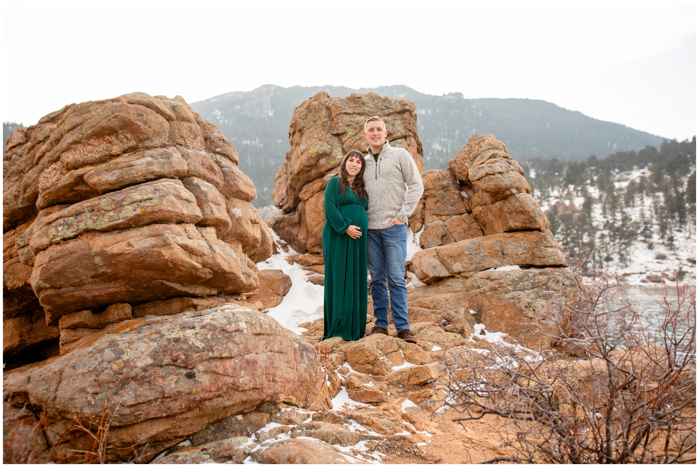 couple posing on rock formations at Mary's Lake during Estes Park Colorado winter maternity photos 