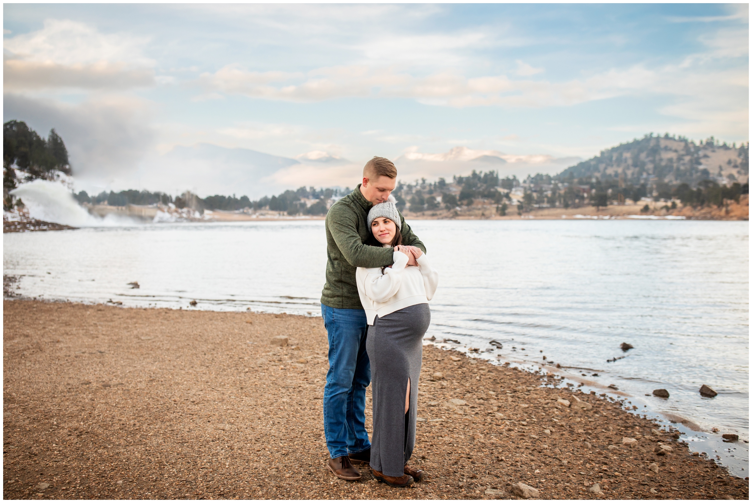 couple embracing at mary's lake during Estes Park Colorado winter maternity photos by Plum Pretty Photography