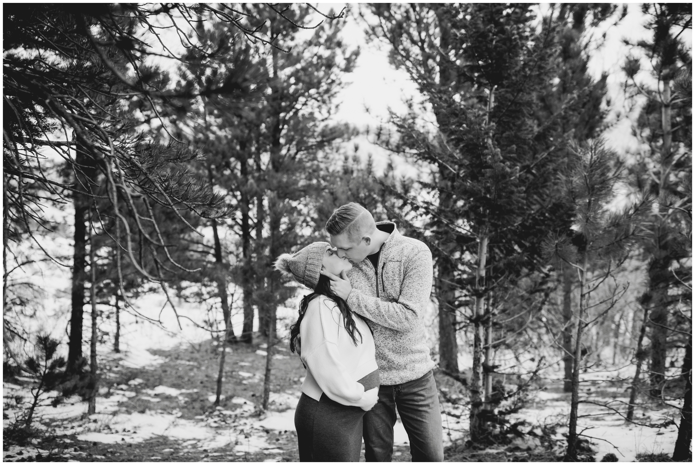 couple kissing in forest during Colorado maternity pictures in Estes Park 