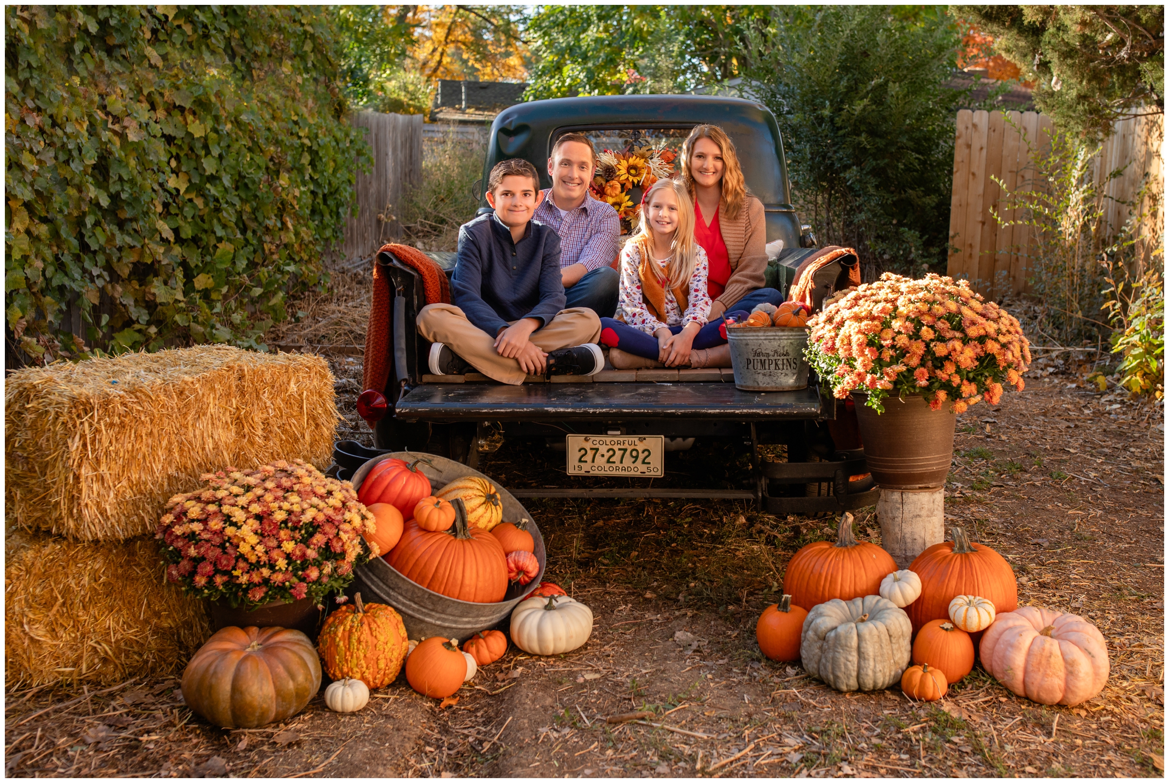 family posing in bed of vintage truck during fall family mini session in Frederick Colorado 