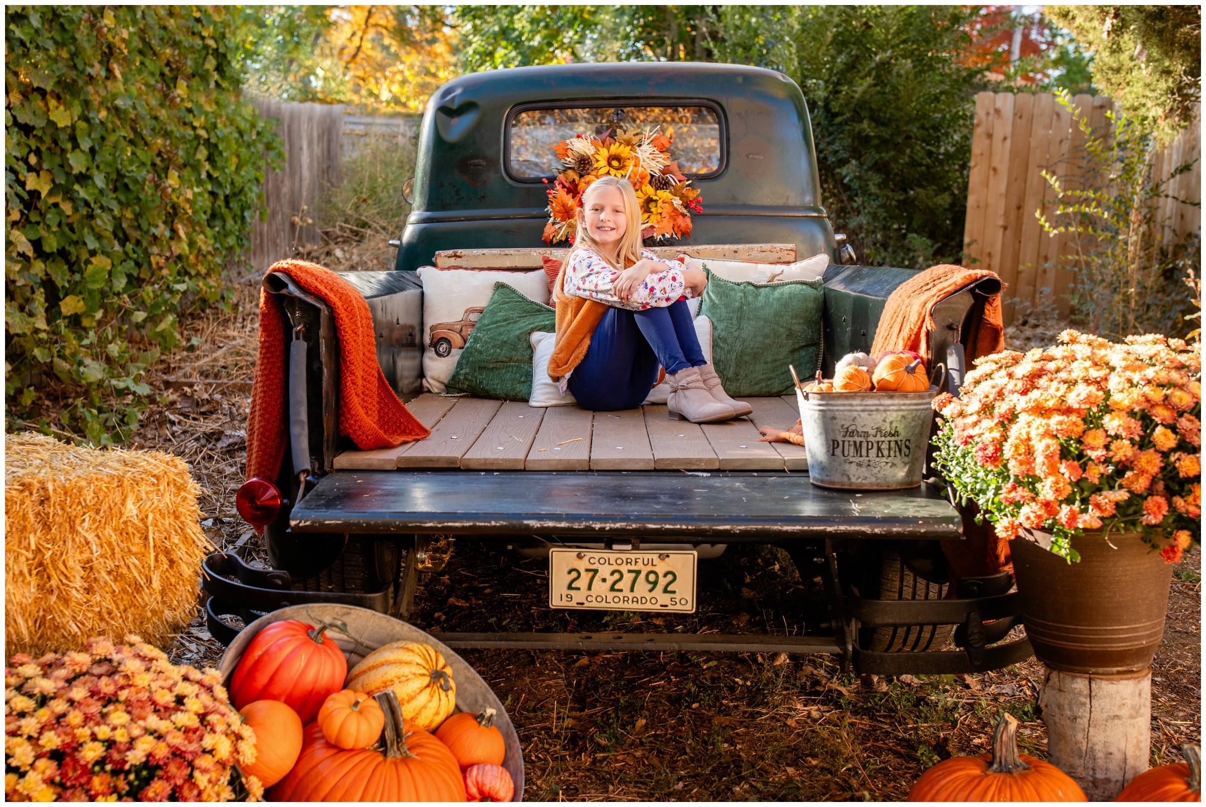 little girl posing in back of a vintage truck during fall family photography mini session in Frederick Colorado 