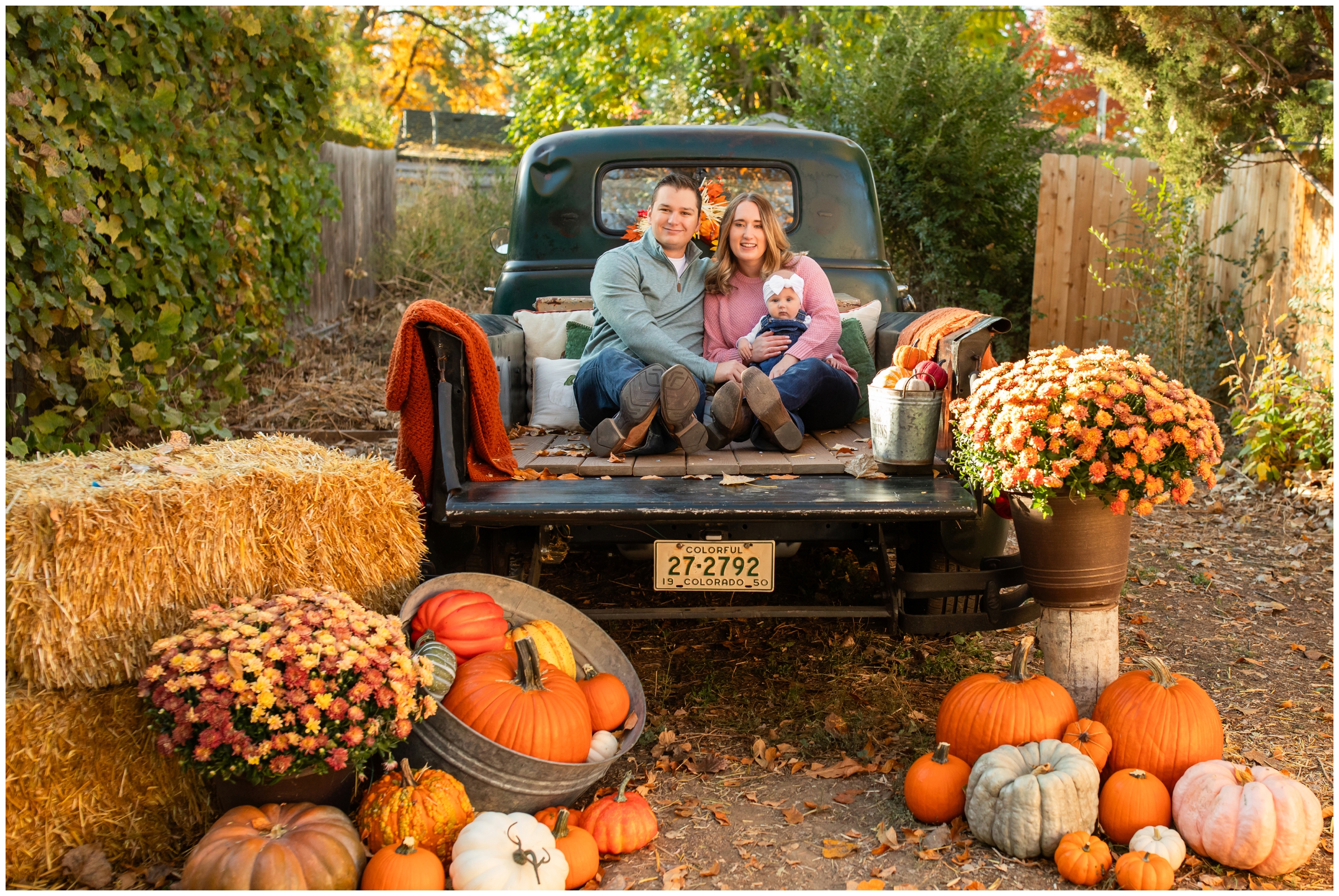 family sitting in truck bed with fall decor all around during family mini session by Frederick Colorado photographer Plum Pretty Photography