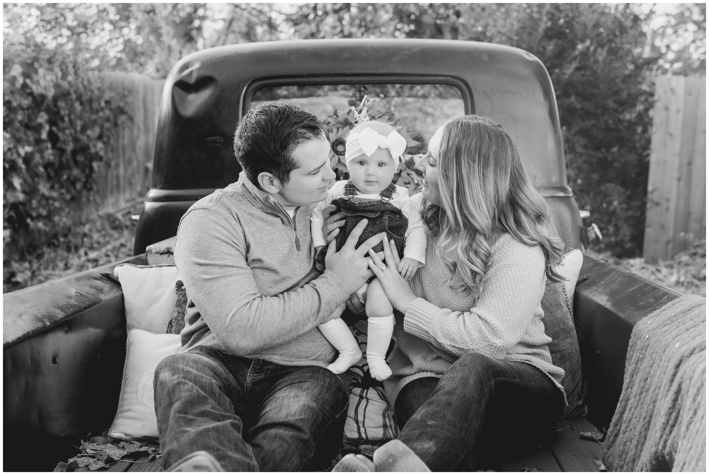 family sitting in bed of vintage truck during fall mini sessions in Frederick Colorado 