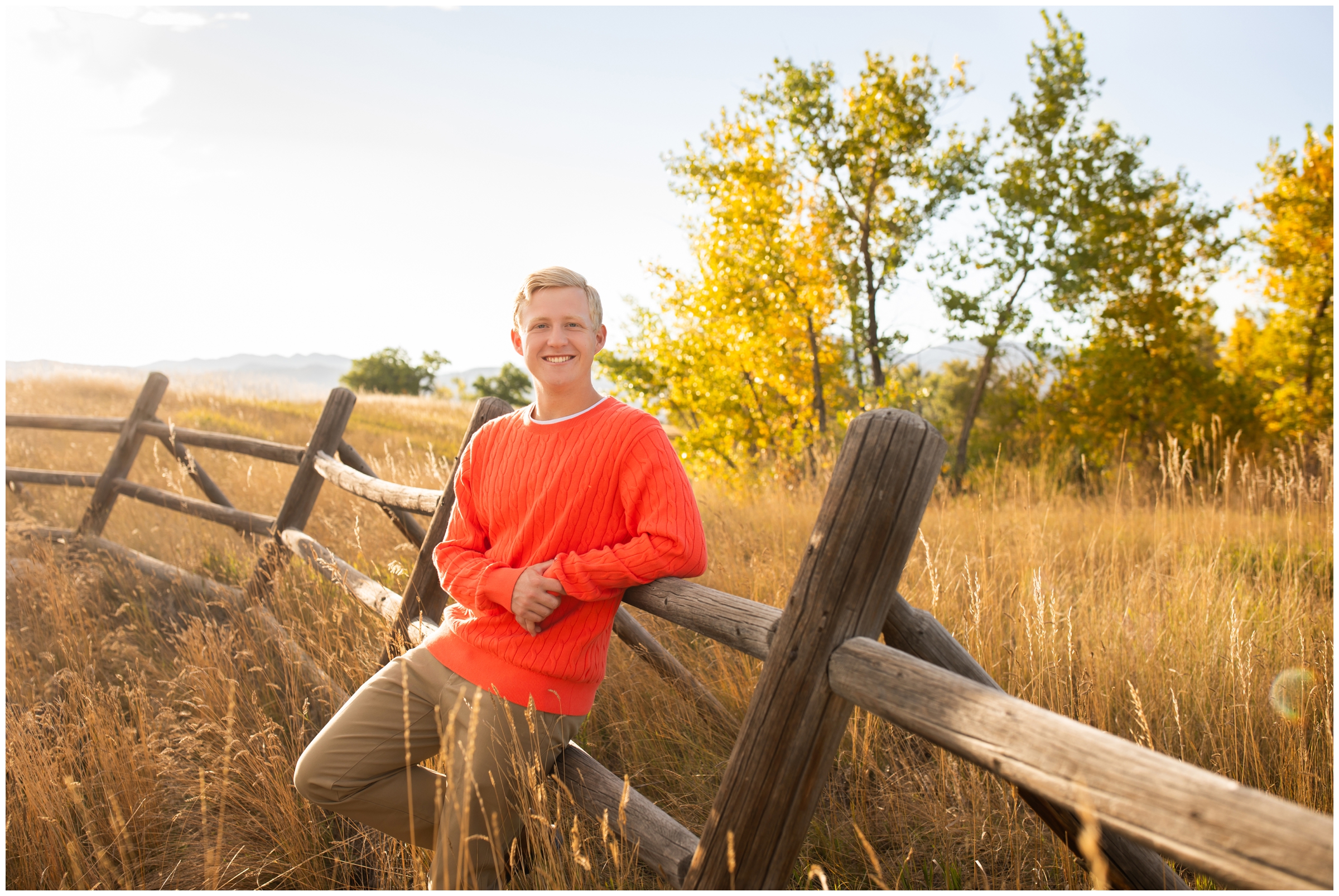 senior guy leaning against wooden fence during Boulder Colorado senior pictures at Coot Lake