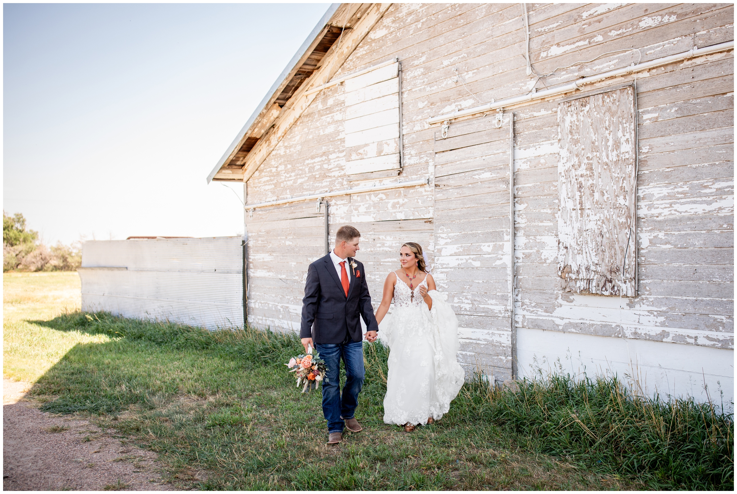 couple walking in front of a barn during candid Colorado wedding pictures by Plum Pretty Photography 