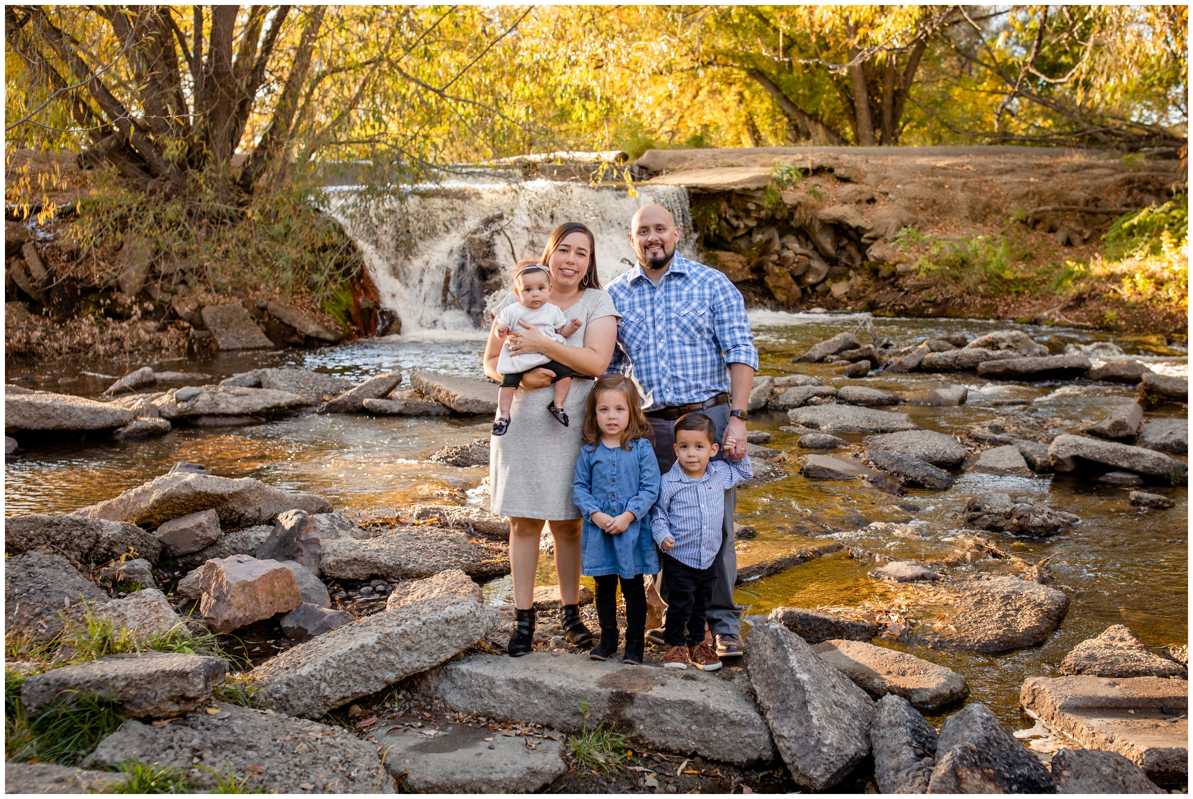 family posing in front of waterfall at Golden Ponds during Longmont fall family photos 