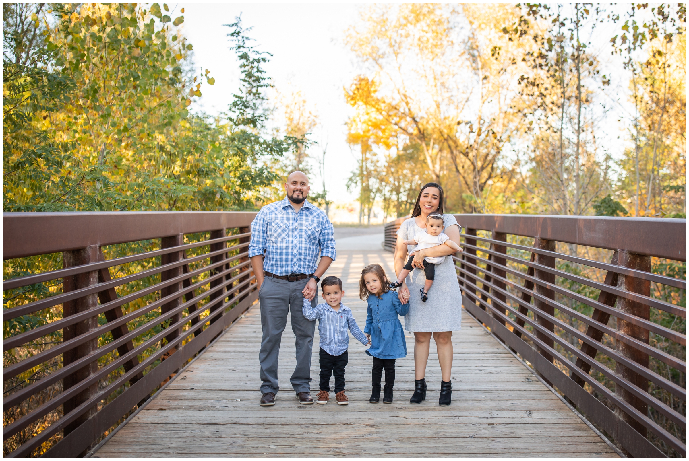 family posing on a bridge at Golden Ponds during Longmont fall family photos by Plum Pretty Photography
