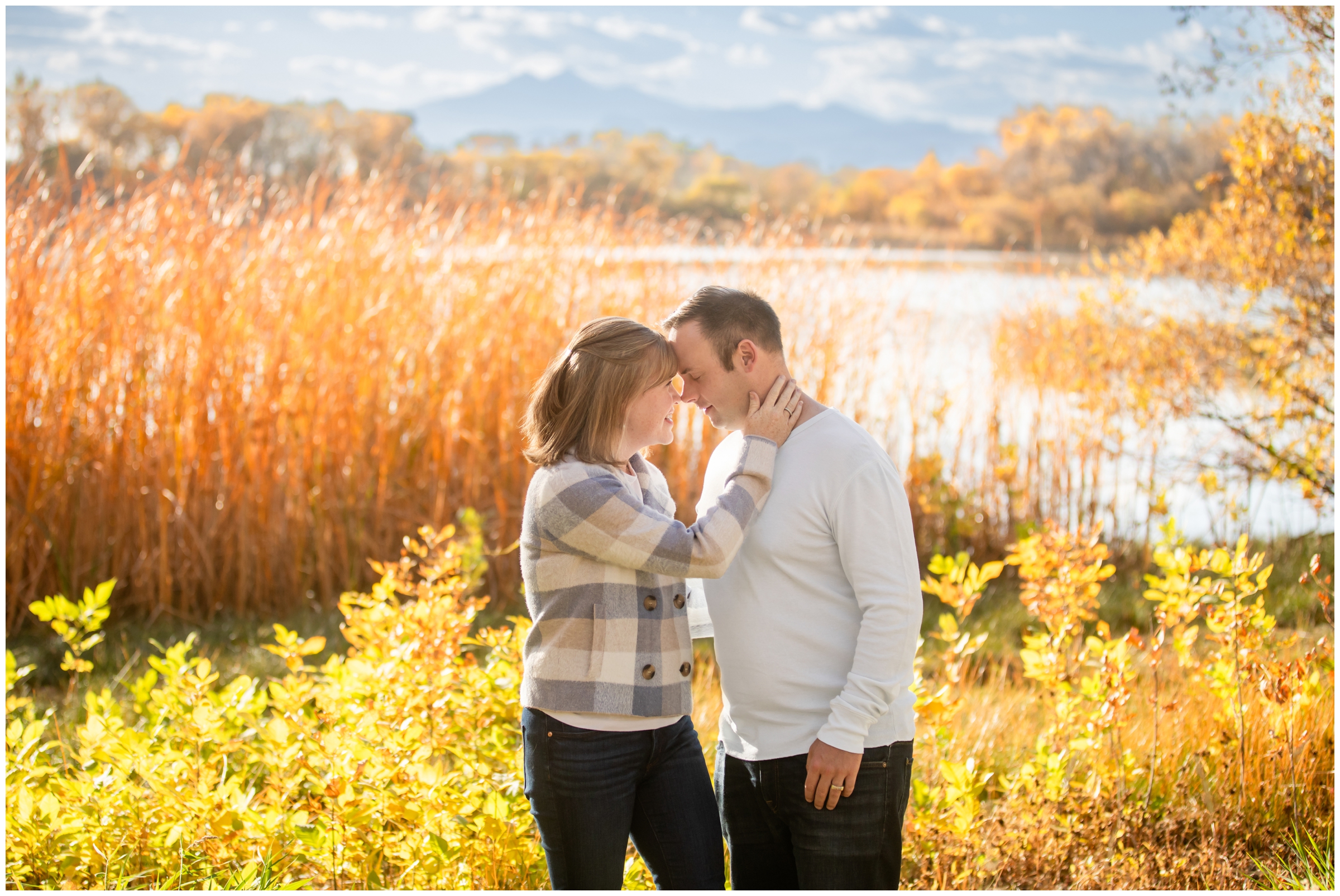 couple embracing in front of mountain lake during Colorado couples portraits at Highland Lake in Mead
