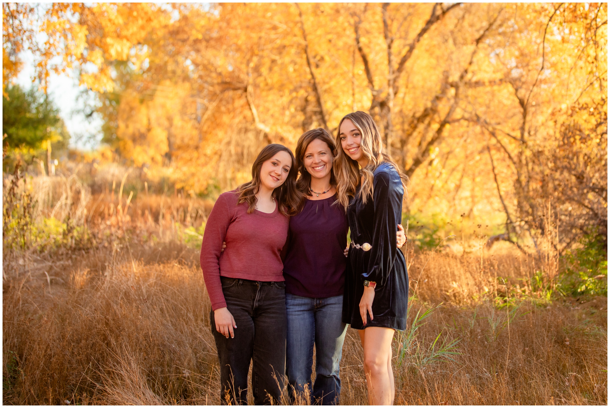 mom and daughters posing in front of fall foliage during Mead Colorado family photos at Highland Lake