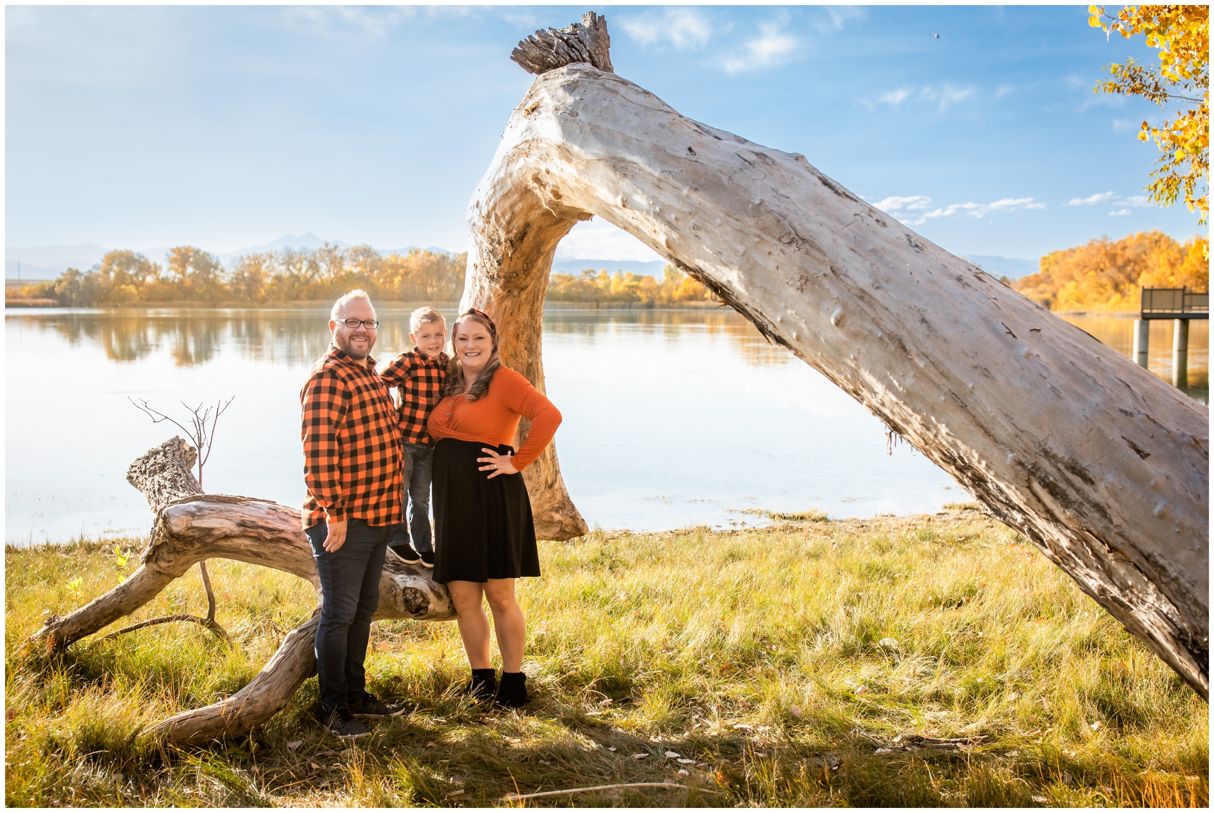 family posing in front of downed tree at a lake in Northern Colorado during fall family portraits 