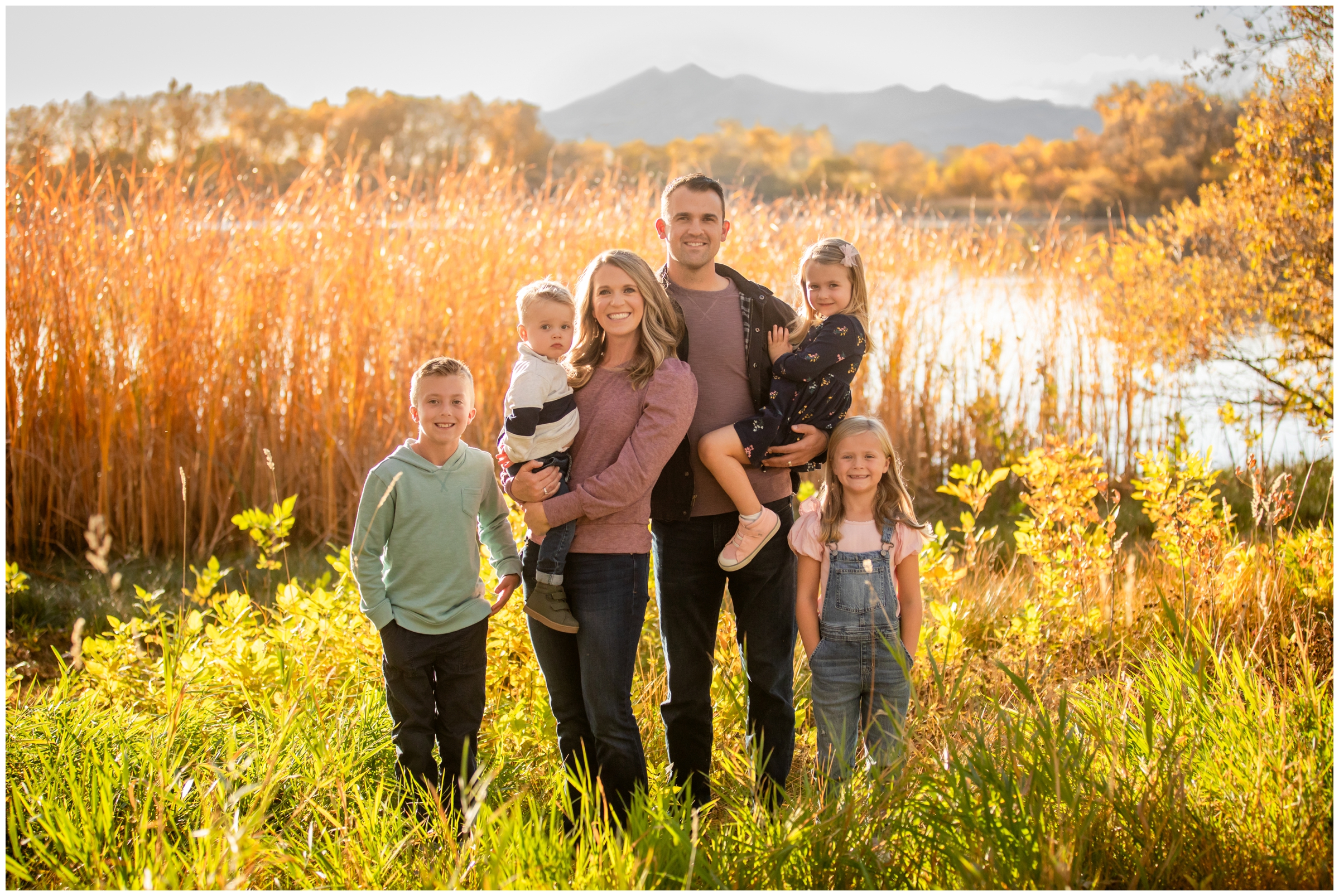family posing in front of mountain lake during Mead Colorado fall family portraits by Plum Pretty Photography