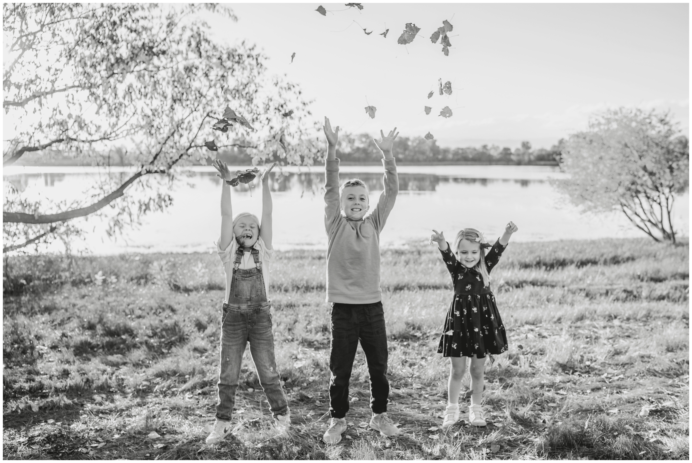 kids throwing leaves in the air during candid family photos at Highland Lake in Mead Colorado 