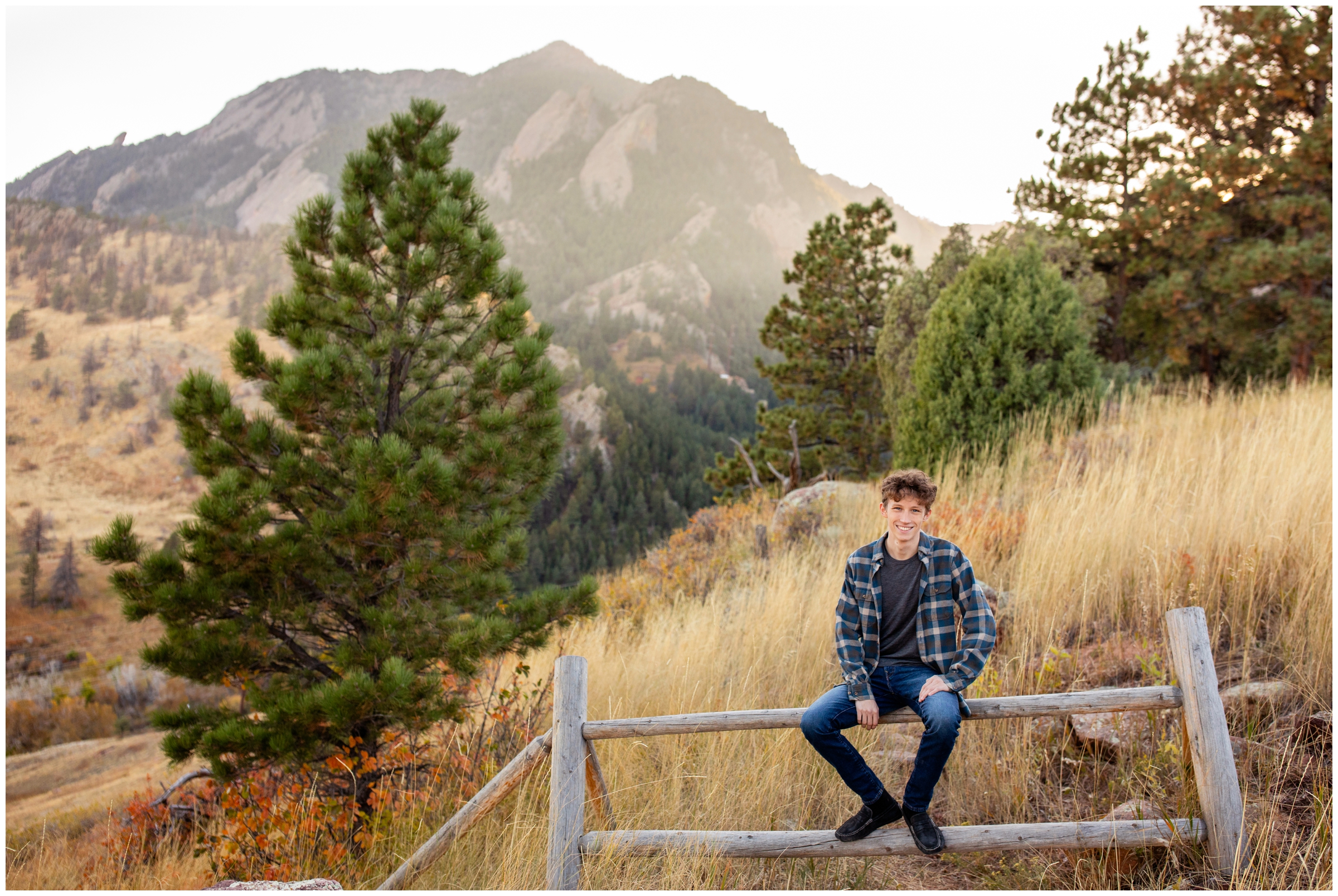 senior guy sitting on fence during NCAR Boulder senior photos by Plum Pretty Photography