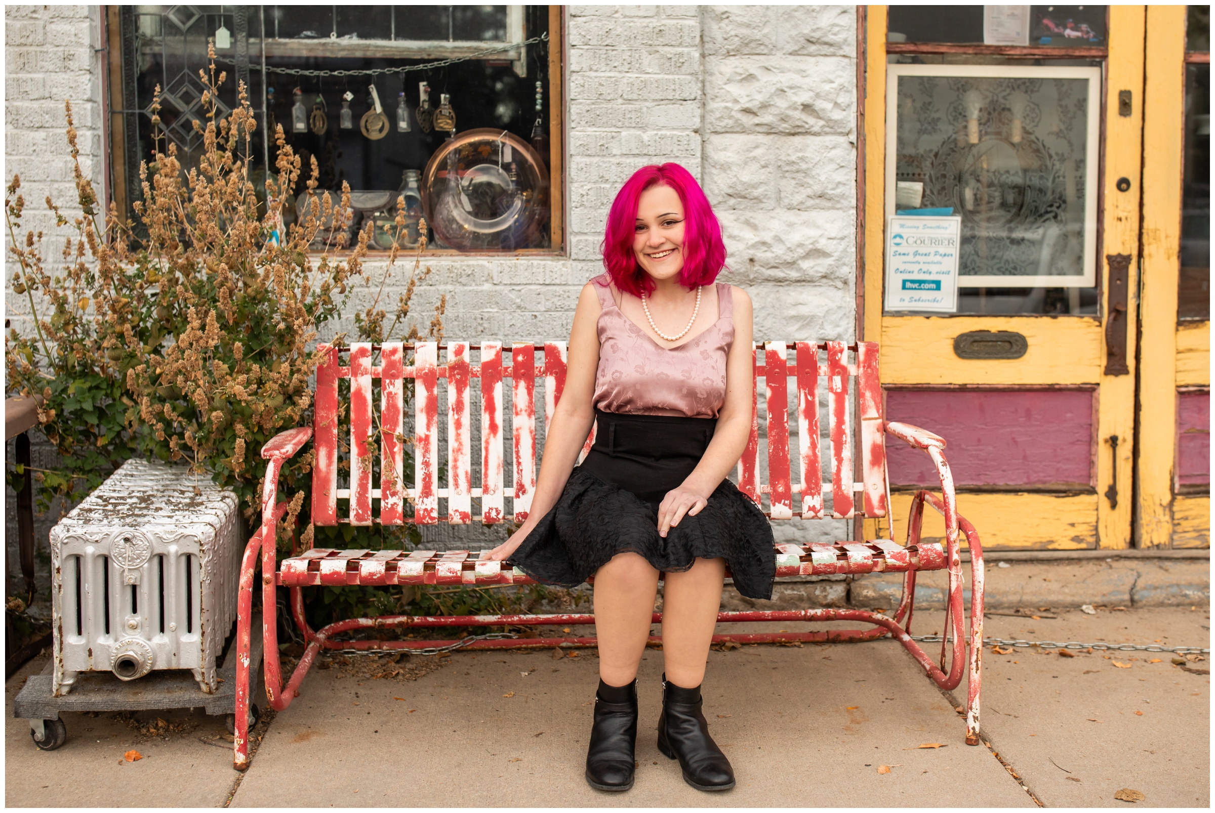 teen sitting on bench outside antique store during artsy senior pictures in Niwot Colorado 