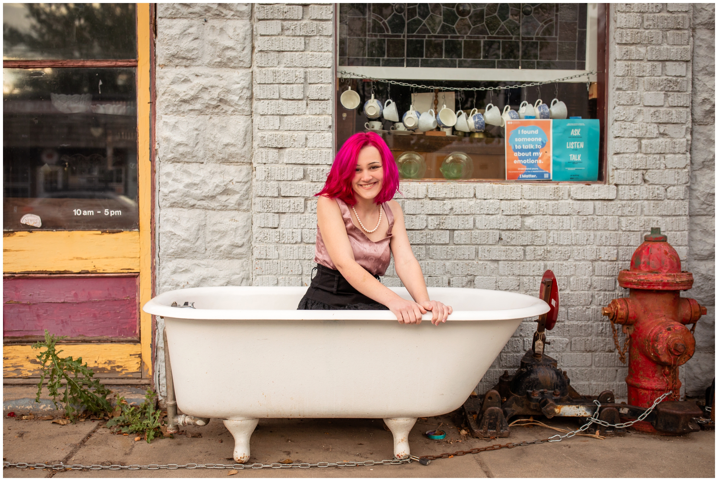 teen with hot pink hair posing with antiques during unique artsy senior photos in Niwot Colorado