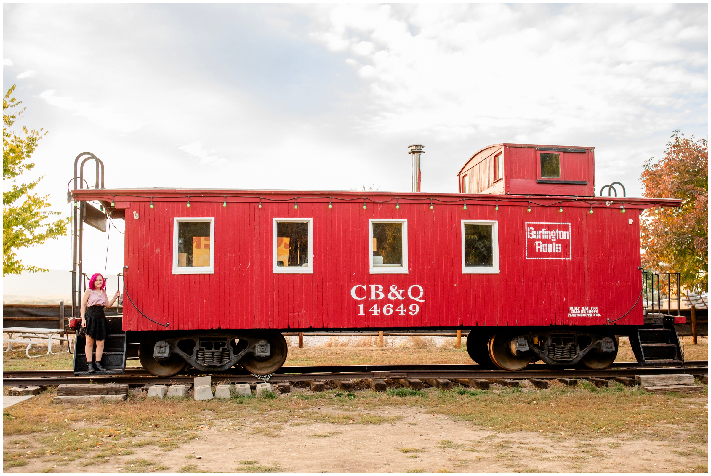 teen posing with train caboose during unique senior pictures in Norther Colorado 