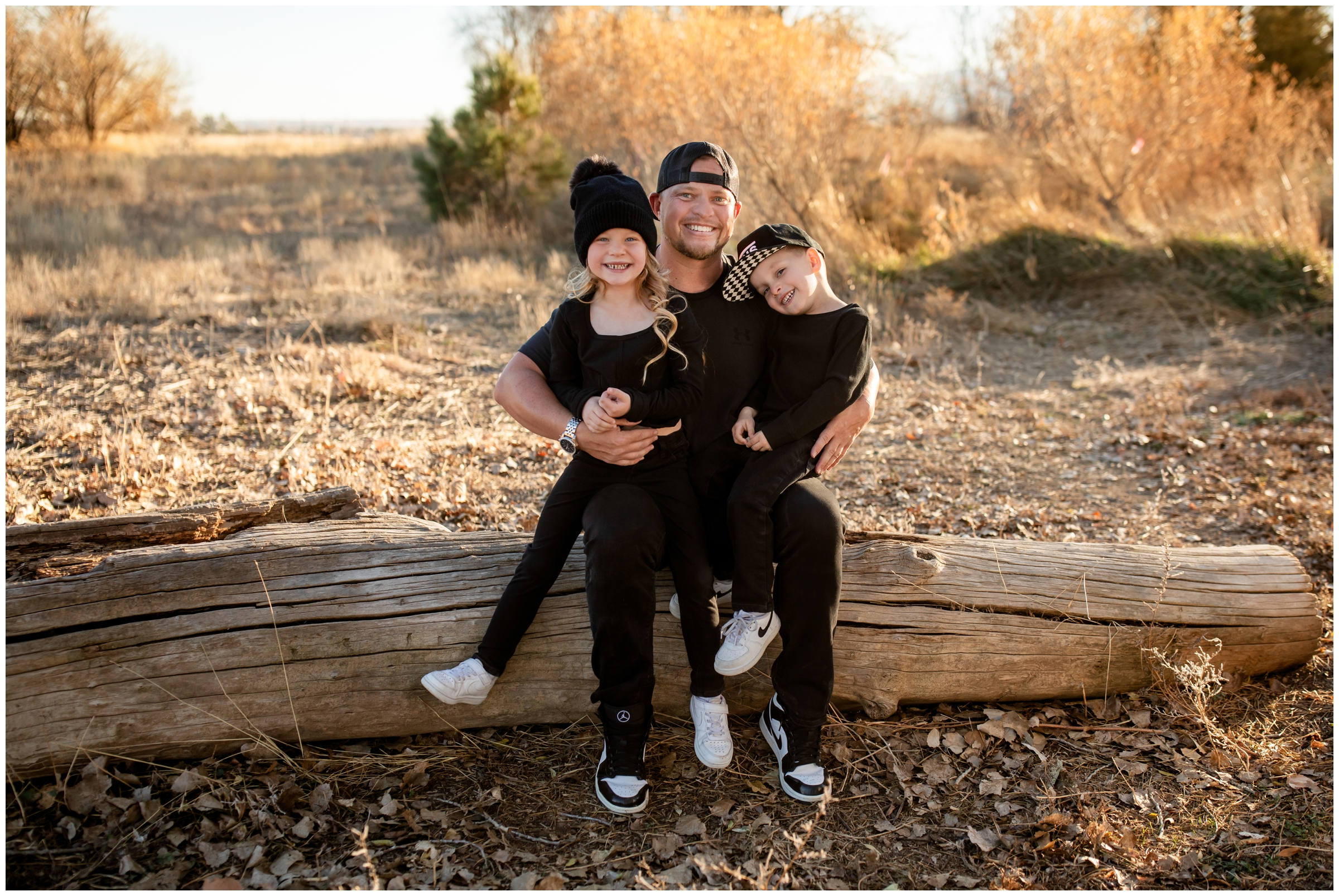 dad and his kids sitting on downed tree during Boulder fall family photos by Plum Pretty Photography