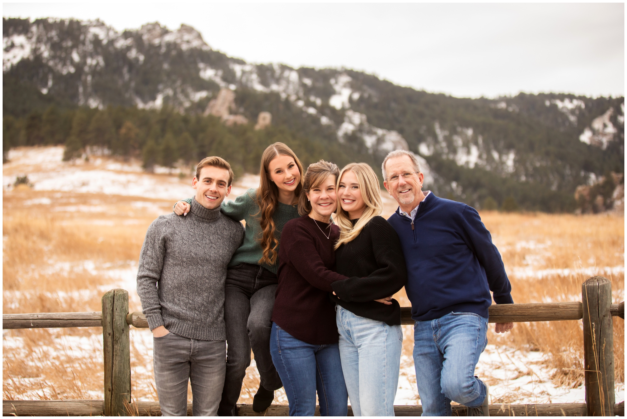 family posing with wooden fence with flatirons in background during Boulder Colorado family pictures 