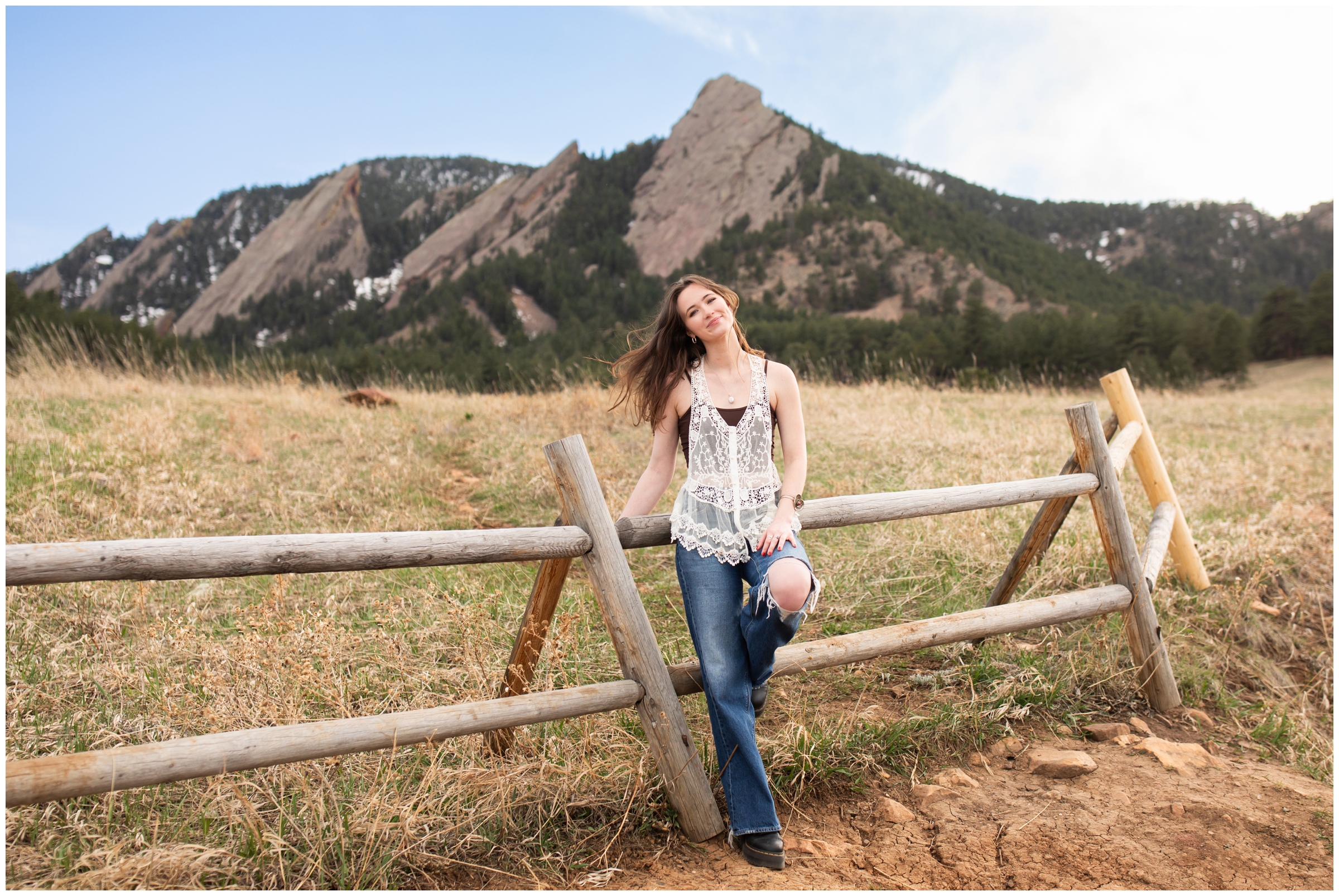 woman leaning against wooden fence during college senior photos in Boulder Colorado 