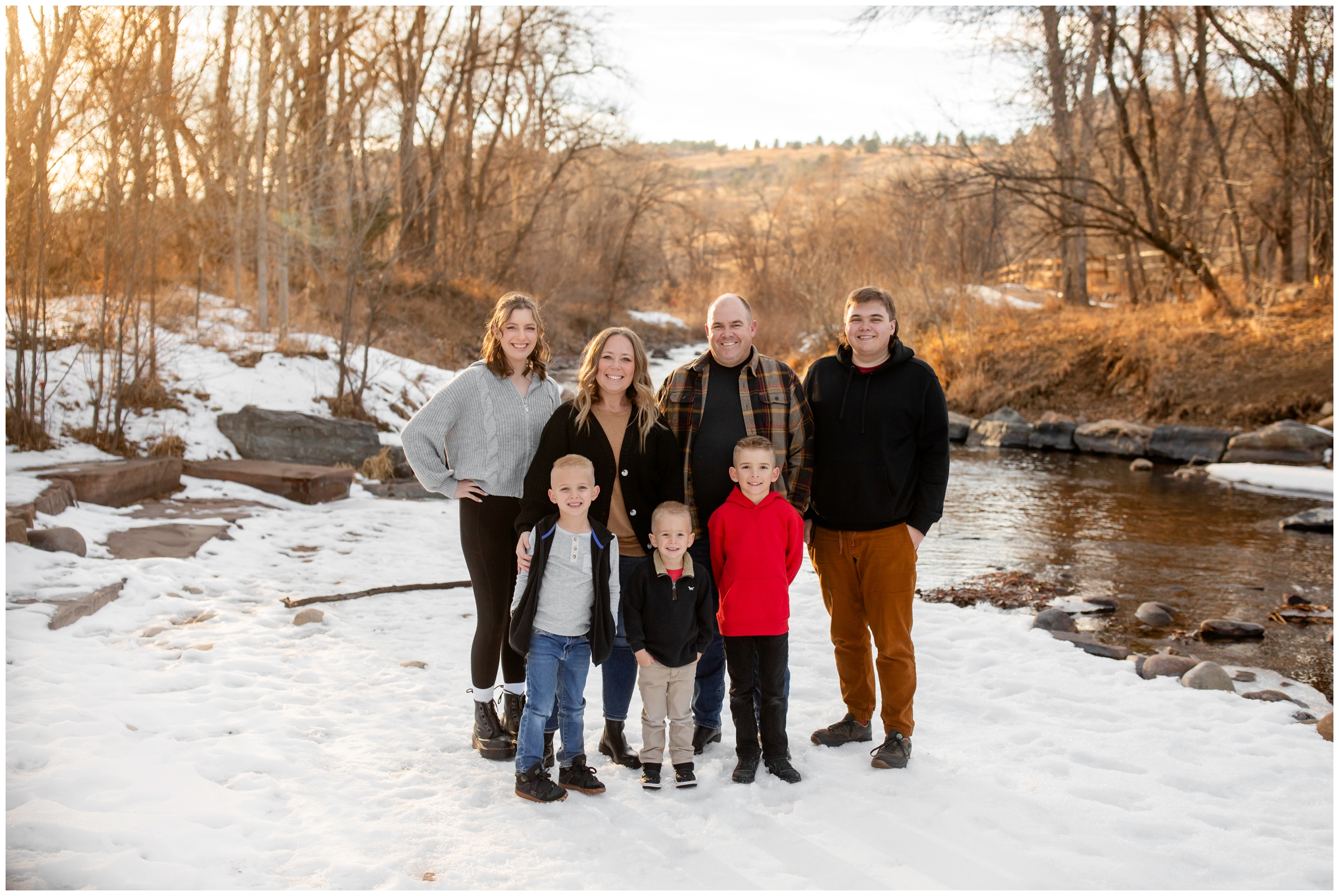 family posing next to a river during winter Lyons Colorado family photography session at Bohn Park 
