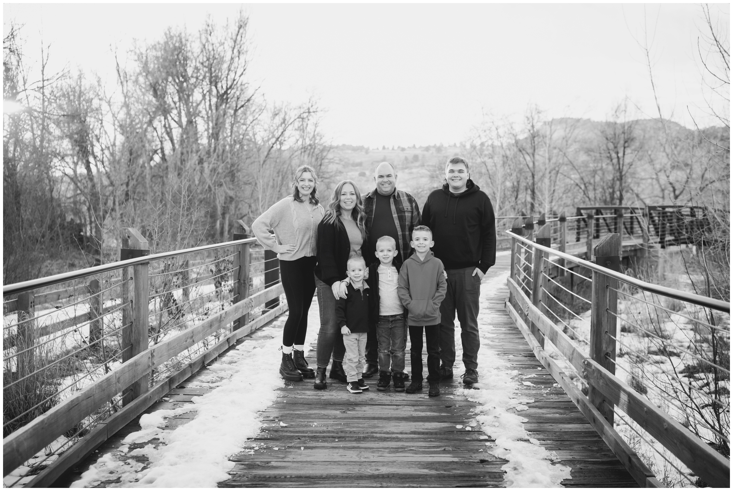 family posing on wooden bridge during winter family pictures in Lyons Colorado 