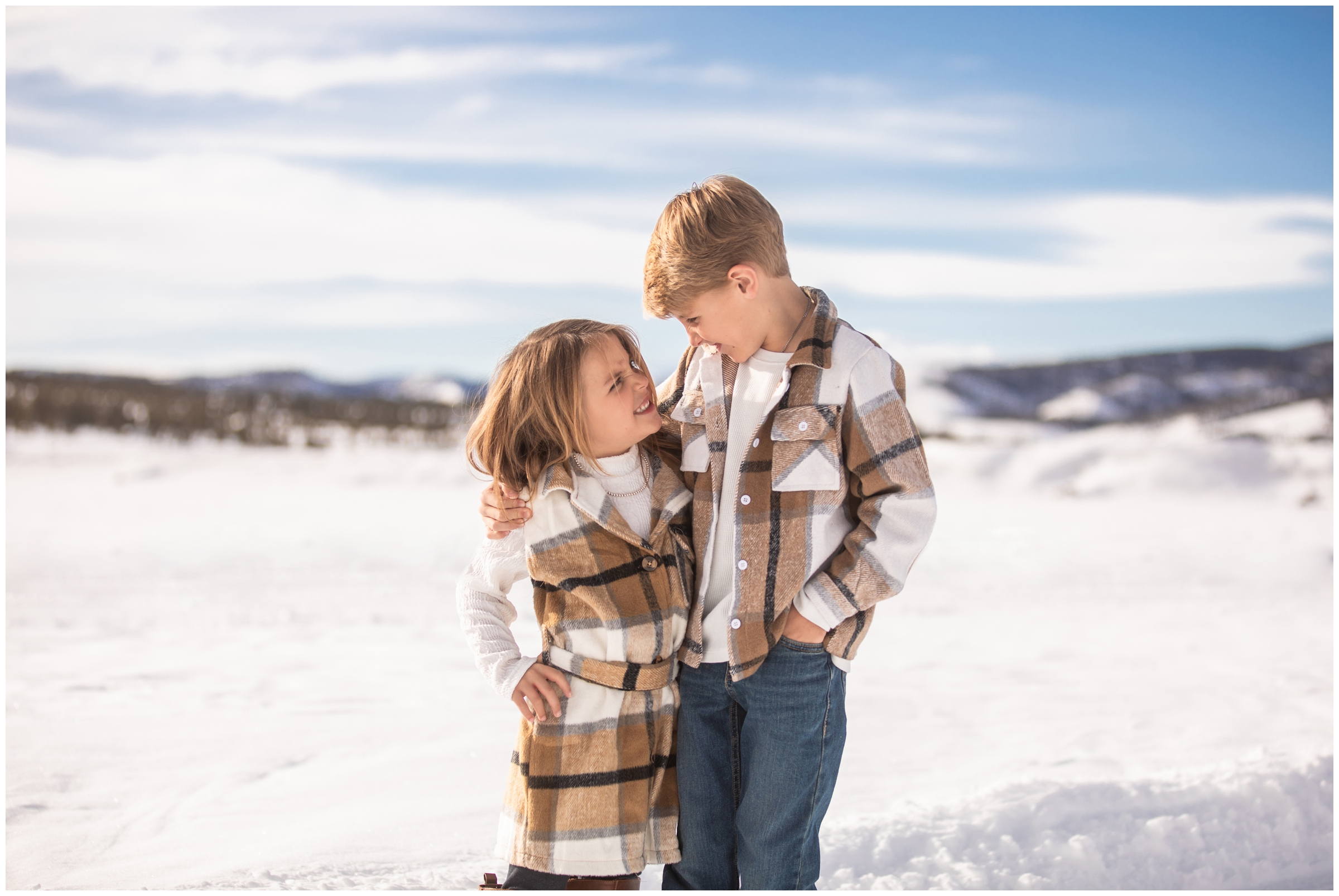 siblings in matching plaid outfits posing in the snow during Winter Park family photos by Plum Pretty Photography